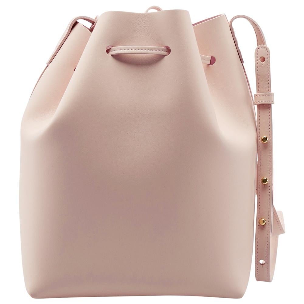 This wonderful Mansur Gavriel design is made from leather and enhanced with gold-tone hardware. The bag has a bucket shape with a drawstring closure that secures the leather interior. It is complete with a shoulder strap. Pink in color, it is an apt