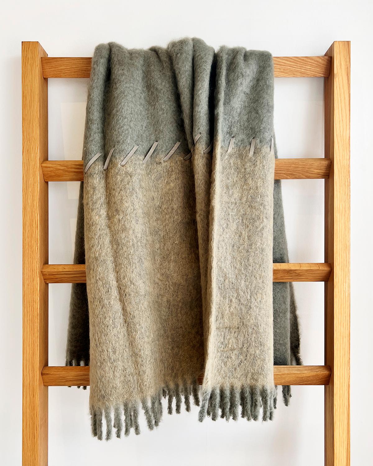 This Sage and Moss Mohair Blanket is crafted with mohair and features two-toned medium green and light green colors with a suede whipstitch accent. It's soft and cozy, perfect for the winter season, and its classic design makes it an excellent