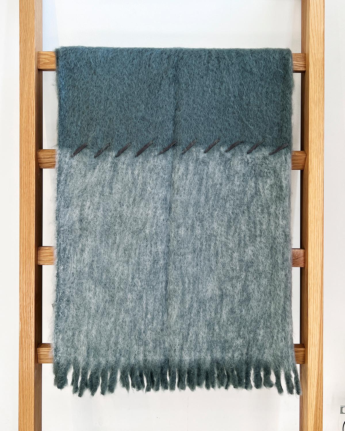 This cozy and warm Steam and Smoke Mohair Throw is perfect for home décor. The soft and fuzzy mohair features a color block with dark and light gray hues, designed to add a chic touch to any bedroom or living room. The suede whipstitch provides a