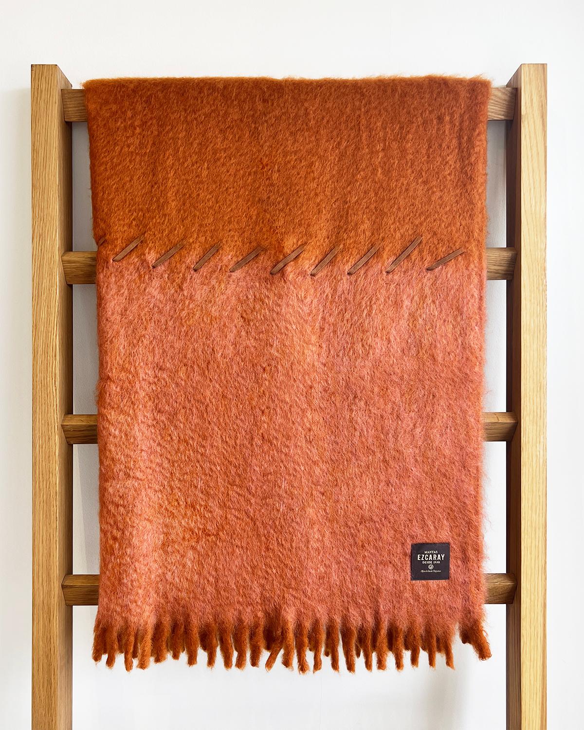 This cozy and warm Terracotta and Brick Mohair Blanket is perfect for home décor. The soft and fuzzy mohair features a color block with red and orange hues, designed to add a chic touch to any bedroom or living room. The whipstitch suede finish