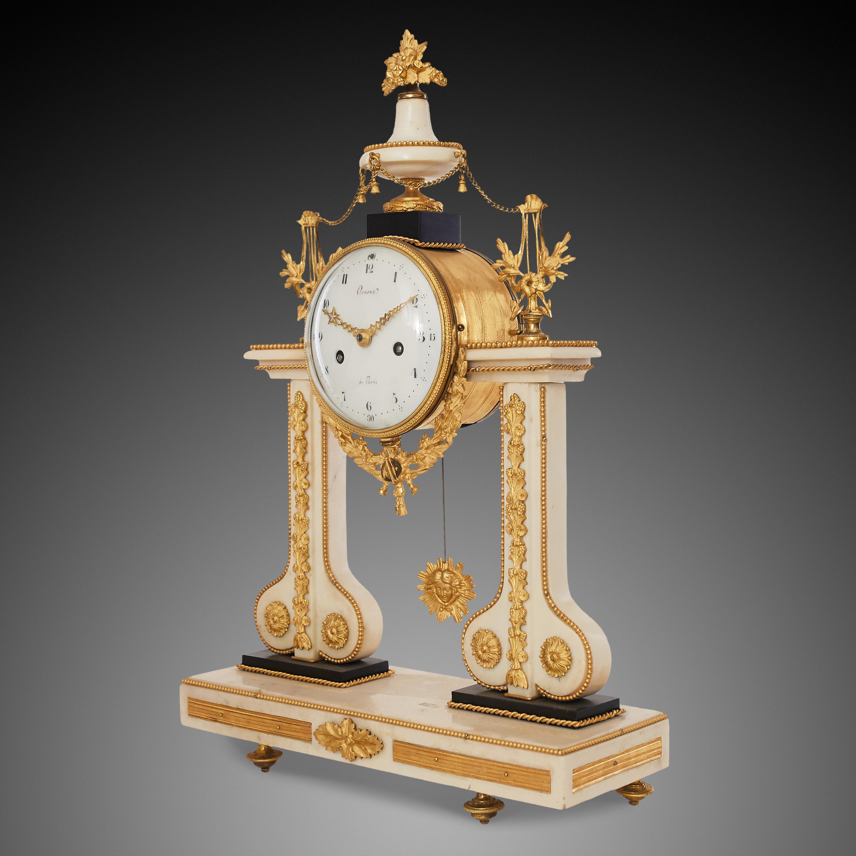 Cette élégante horloge portique de style transitionnel Louis XVI - Eleg, réalisée en bronze doré, marbre blanc et noir, est signée sur le cadran 