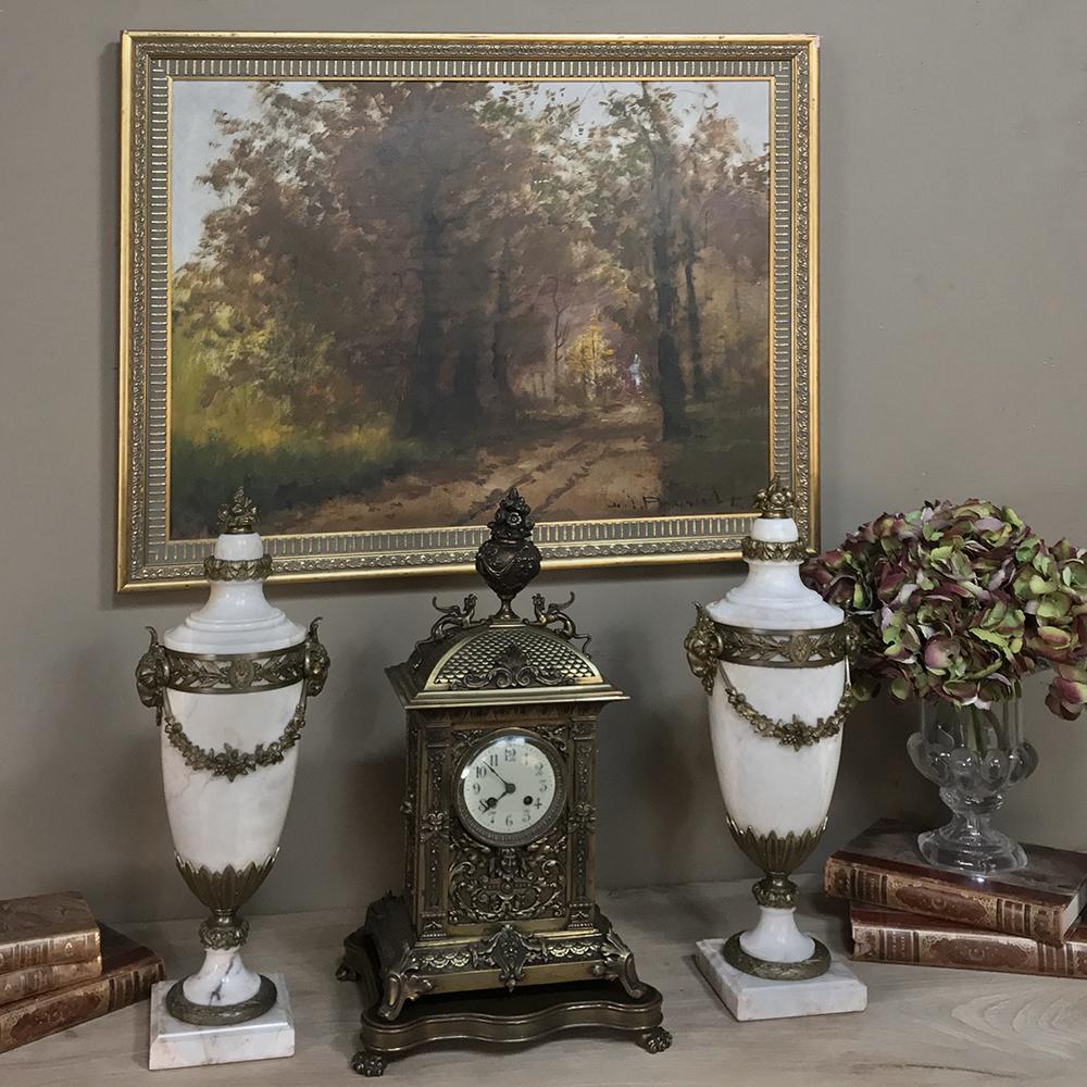 19th century French Louis XVI mantel clock is a marvel of the metalsmith's art, featuring a gloriously detailed urn bursting with flowers and draped with ribbon and fabric situated atop a fish scale-shingled arched roof and guarded by long tailed