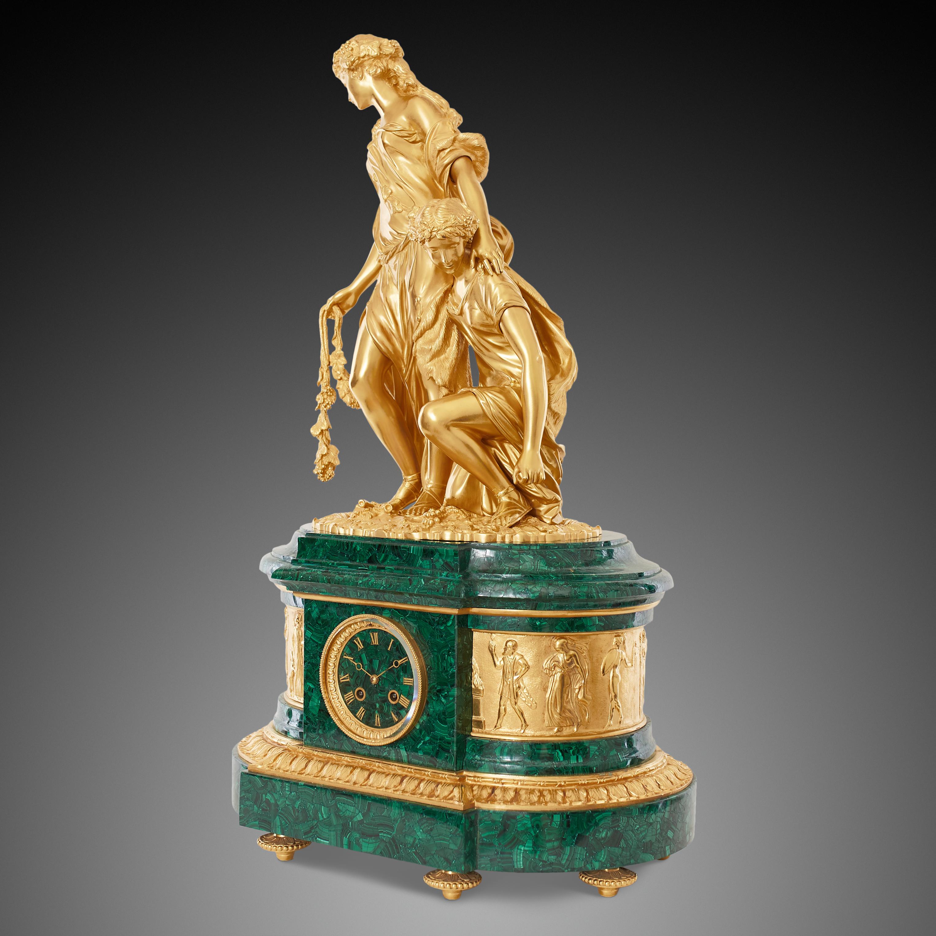 Late 19th century neoclassical style clock crafted from gilt bronze with malachite. The central clock features a striking ormolu sculptural surmount, depicting two female figures, dressed in classical Greek draped garment, and holding a grapevine.