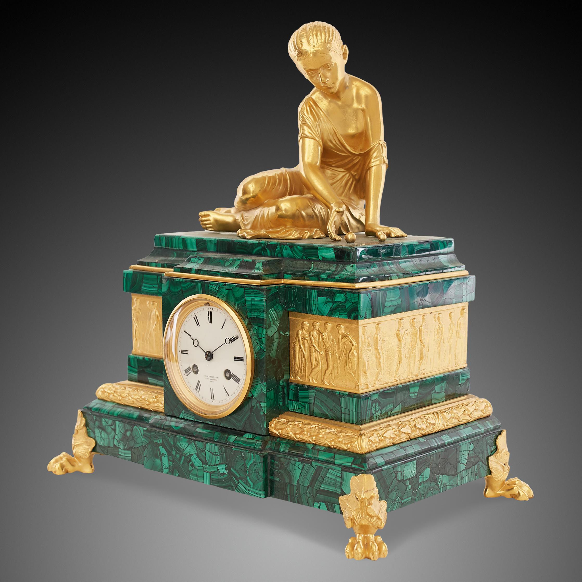 A beautiful clock made of bronze and malachite with an intense color. The clock has four decorated legs and on its top there is a figure of a sitting woman in golden color. The clock is in excellent and perfect working condition. In addition, it has