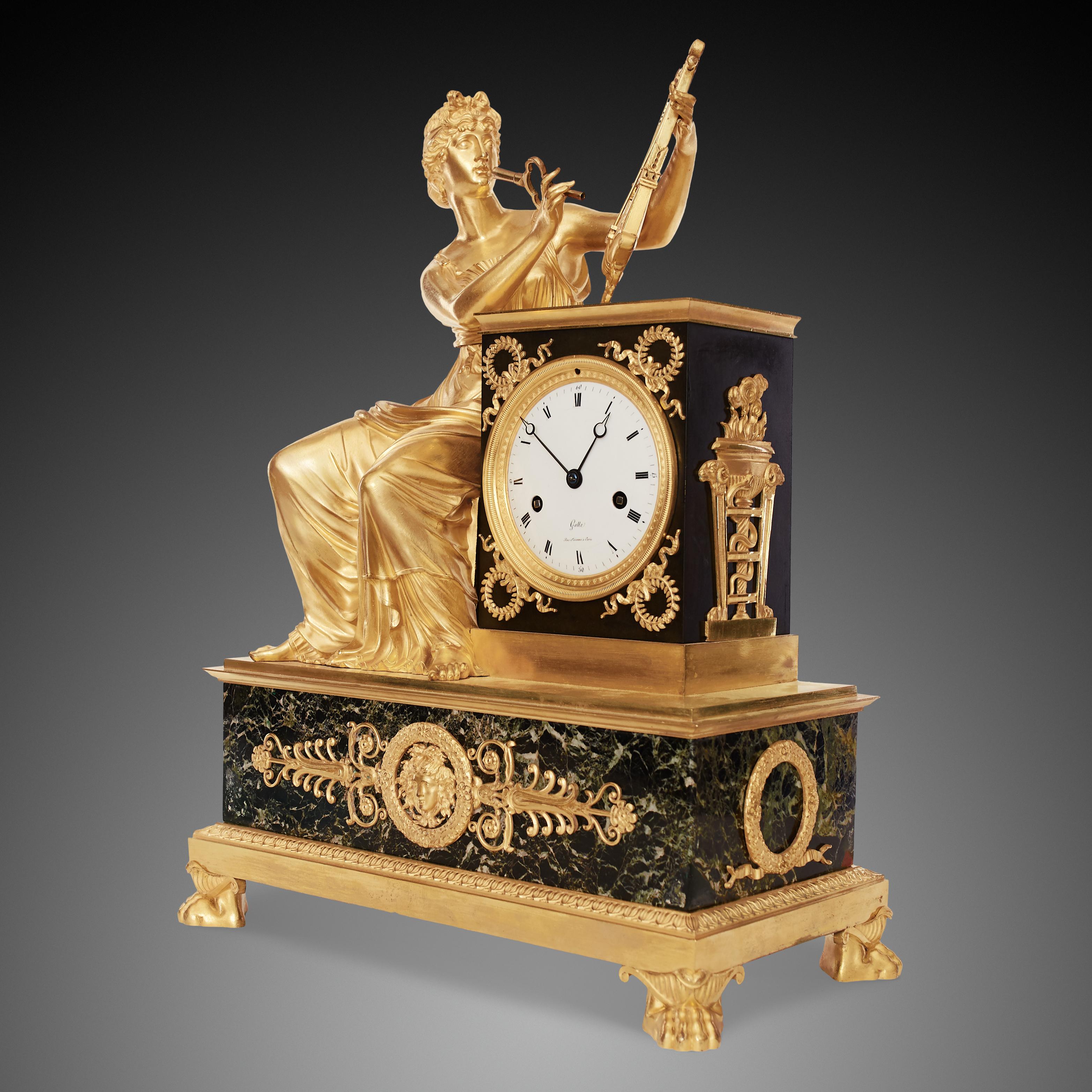 This is a beautiful antique French Empire mantle clock was made of gilded bronze and marble. The clock is placed on a rectangular marble pedestal, with four legs in the shape of a lion's foot. The white enamel dial signed “Galle, Rue Vivienne à