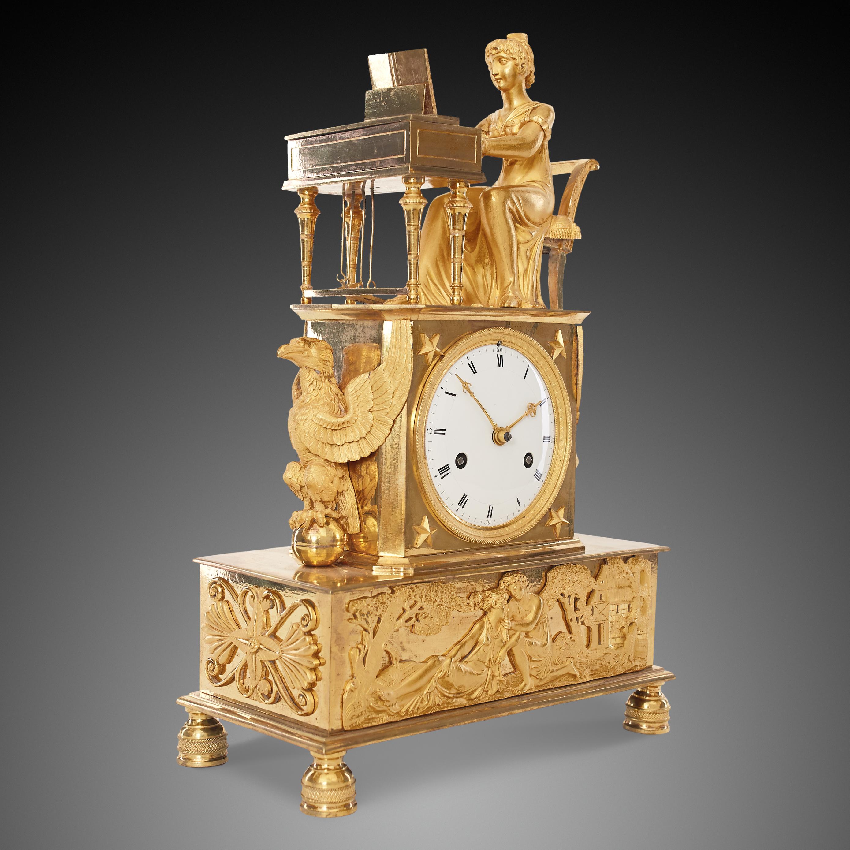 This nineteenth-century gilded bronze clock exemplifies the grandeur of the Empire style, featuring a rectangular base with four legs, each intricately carved with subtle patterns. Atop the clock, a finely detailed figure of a lady is shown playing