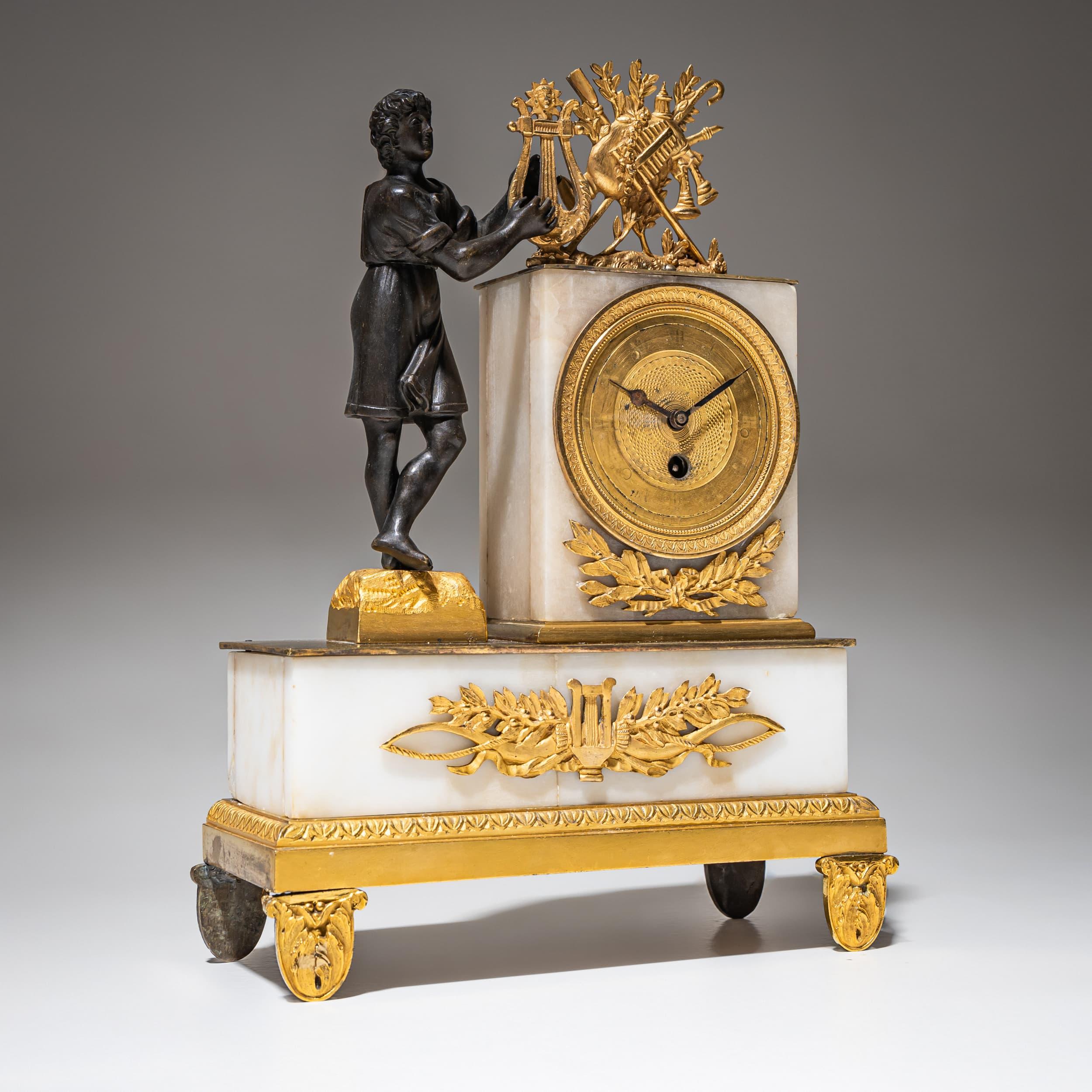 Neoclassical mantel clock composed of patinated and fire-gilded bronze with white marble. The movement is positioned on the right, finely chiseled and adorned with laurel appliqués. Atop the clock sits a decorative arrangement of musical