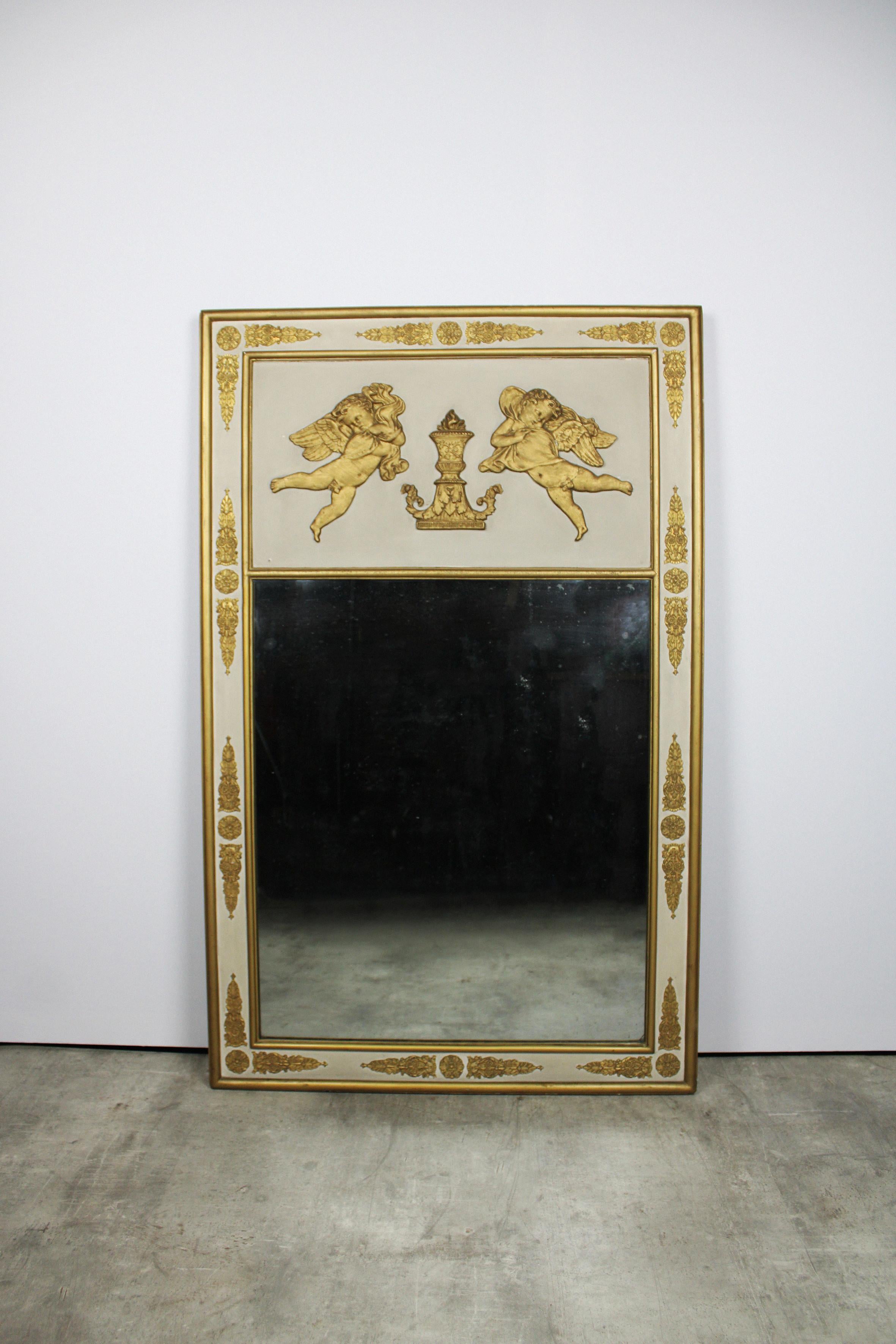 This 19th century mantel mirror hails from France, featuring a wooden and stucco frame adorned with gilded gold leaf. The rectangular pediment enhances the entire piece, showcasing a divine relief scene with two hovering angels and various
