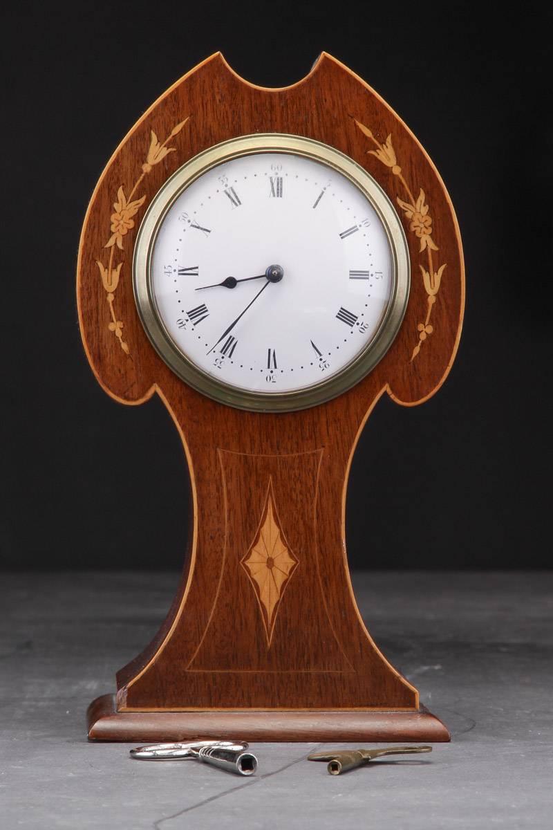 Mantel clock softwood decorated mahogany inlaid in light wood with flowers and foliage. White enameled clock face with Roman and Arabic numerals. Empire style, circa 1900. 
Measures: Height about 10 in (25cm). Good original condition.