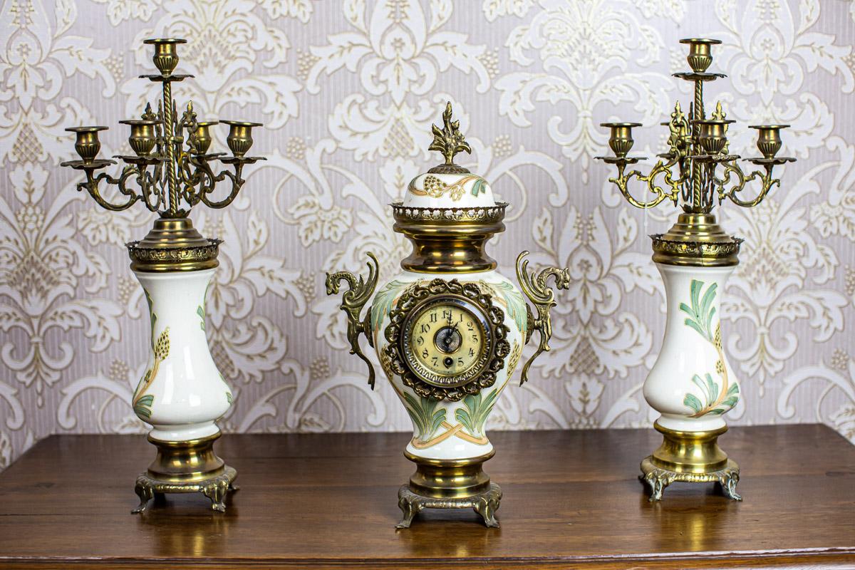 We present you a mantel set composed of a clock and two four-arm candelabras.
The candelabras and clock case are made of ceramic combined with brass.
Moreover, the clock face is covered by glass.

The clock is functional, after a horological