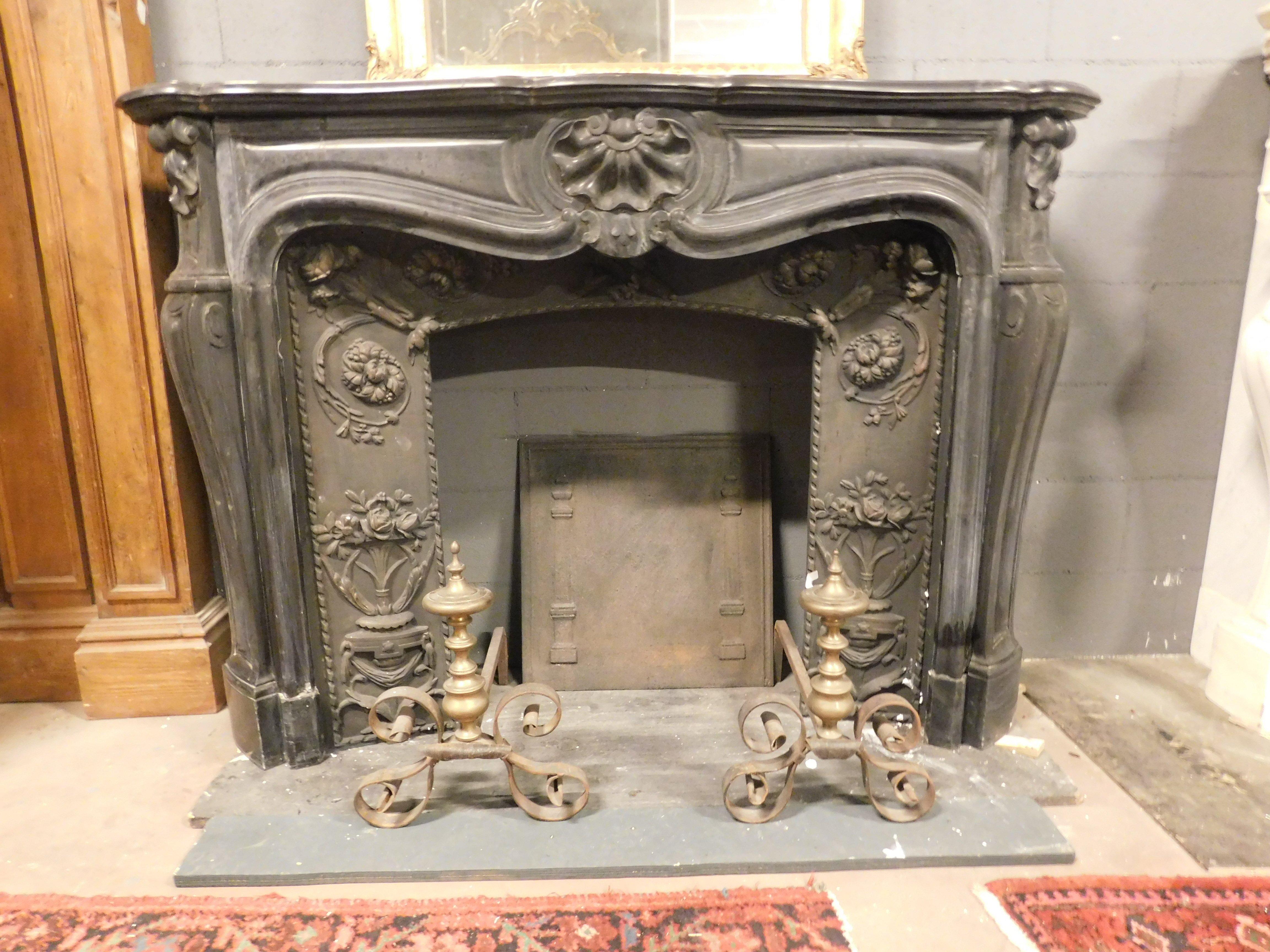 Cheminée ancienne en marbre noir de Belgique, richement sculptée de coquillages. La cheminée a un dessus élégamment incurvé et une façade décorée de coquillages sculptés, celui du centre étant plus grand. Les pieds sont enroulés, avec d'élégantes