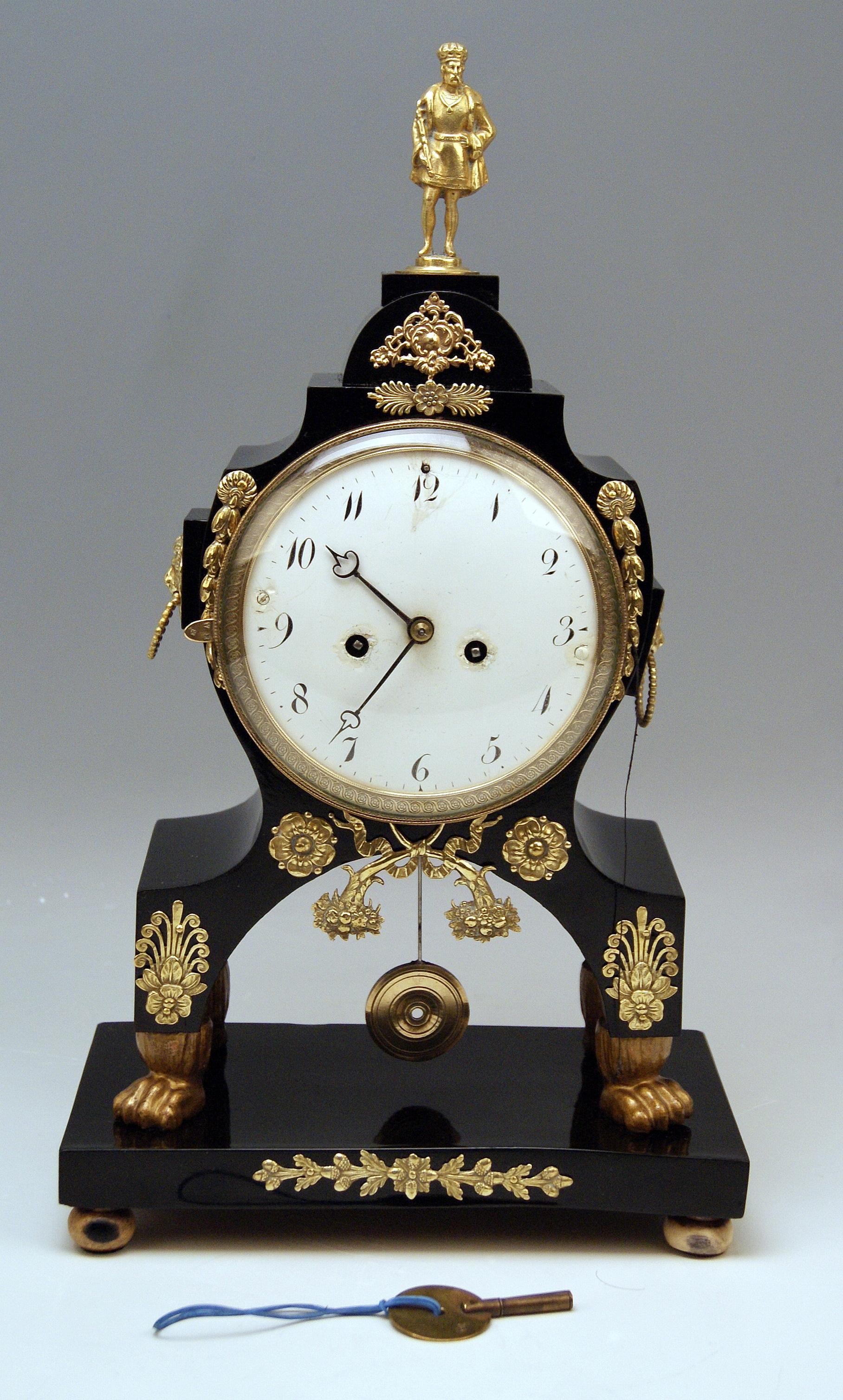 Viennese mantle / mantel / table chiming clock Empire style 

Date of manufacture: circa 1810-1830

Material: 
The clock's chest is made of wood (black stained). Enamel (= the clockface has Arabic numerals) / 
Brass (applied decorations) /