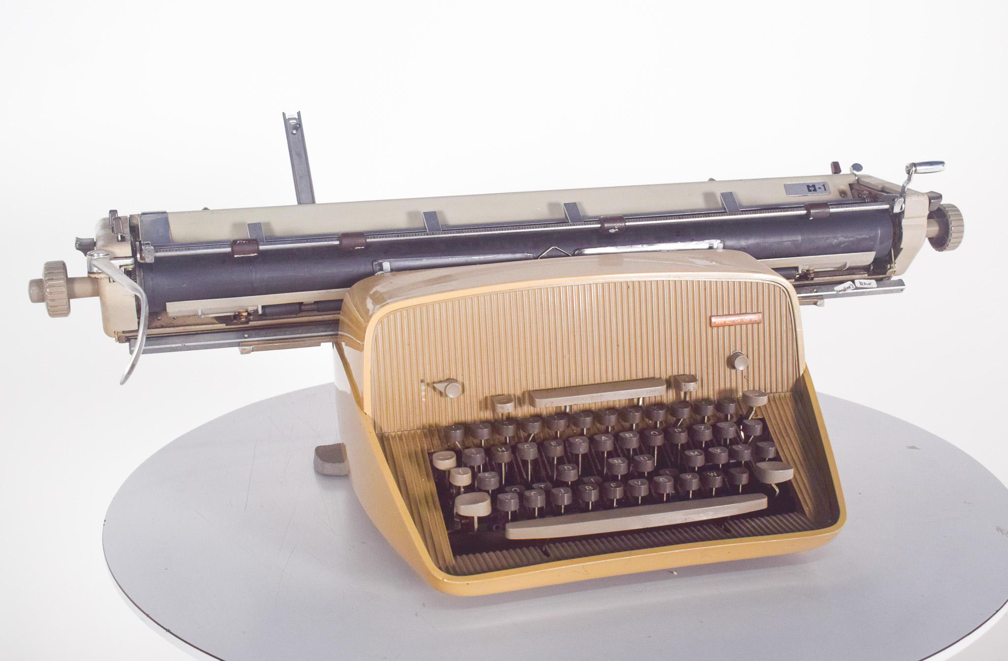 Macchina da scrivere manuale, tastiera HCESAR di MESSA. Con un design robusto, una struttura beige e dettagli in metallo cromato.
La tastiera 