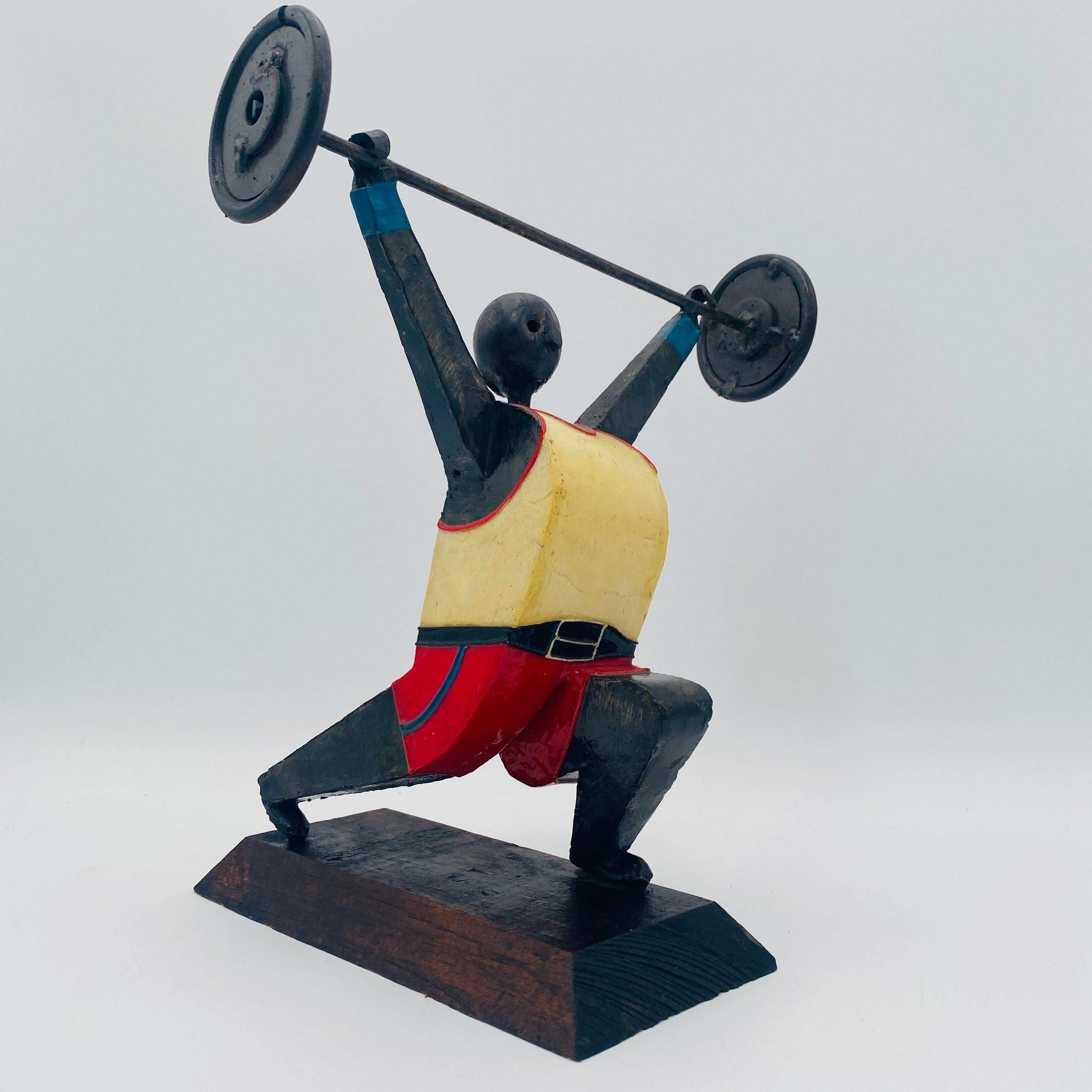 Il s'agit d'une sculpture d'un haltérophile de l'artiste mexicain Manuel Felguérez, réalisée au Mexique vers les années 1970. La sculpture est fabriquée et peinte à la main. Elle est signée 