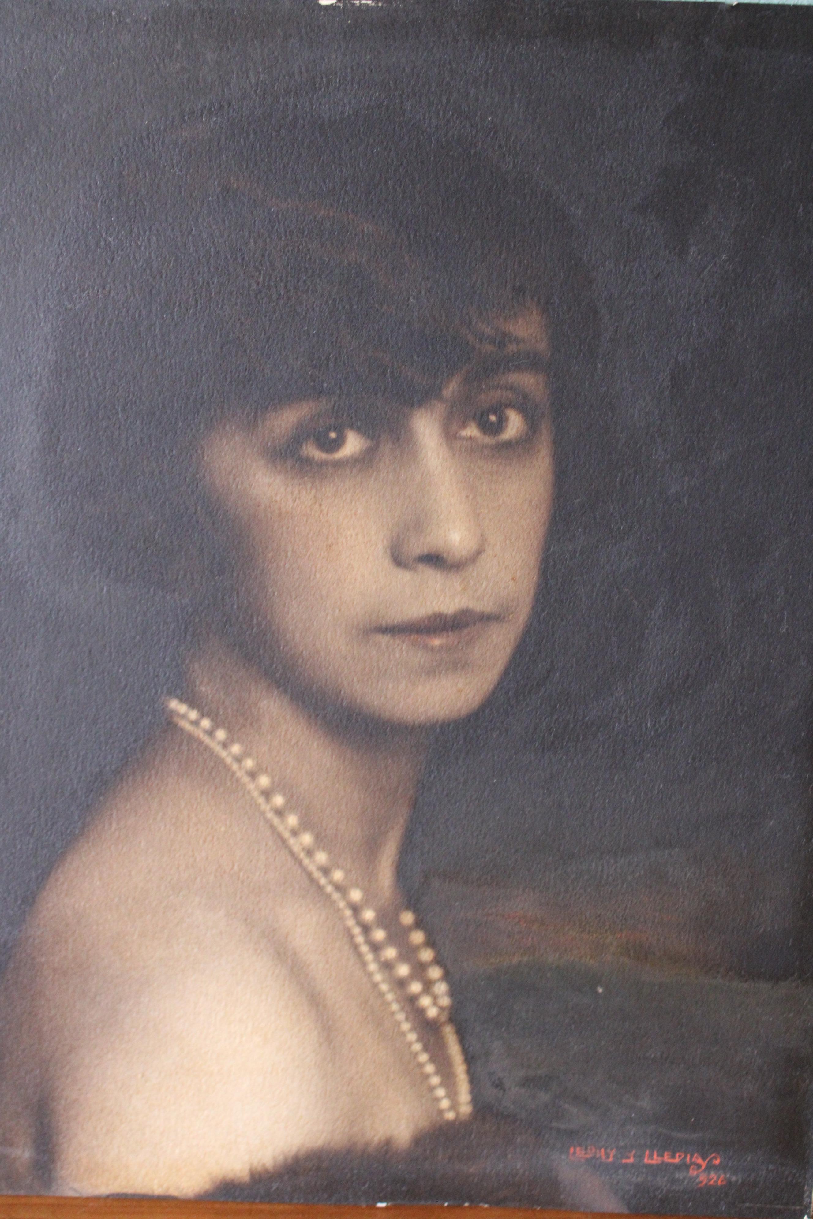 Dark and moody 1920's portrait of a woman named Leony framed under glass and signed by Spanish artist Manuel Lledias (1897-1970).  A very attractive portrait painting capturing a woman with pearls and dark soulful eyes. she is in a thick vintage