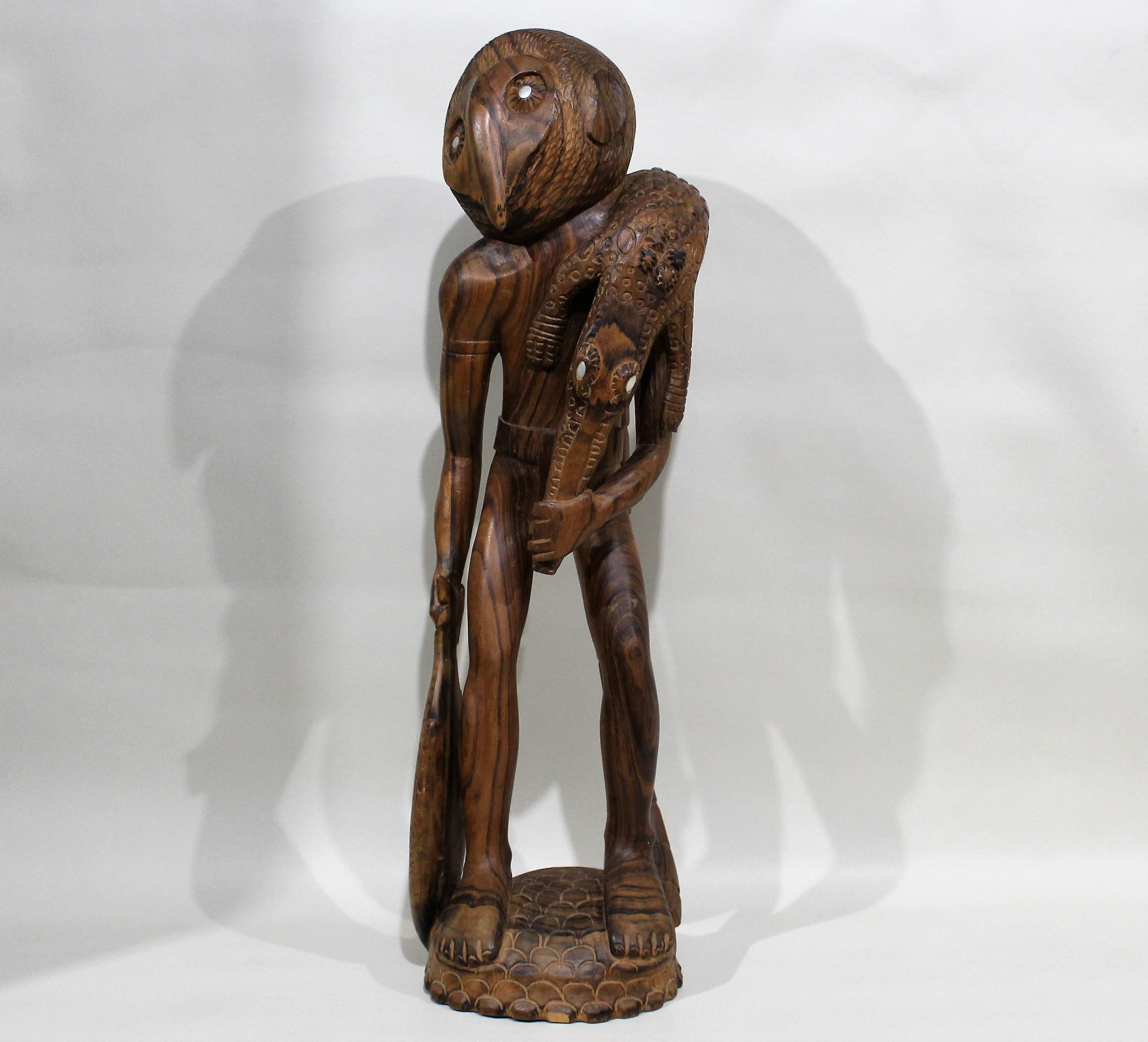 Scultura Maori scolpita a mano di un cacciatore che trasporta un coccodrillo e un pesce.