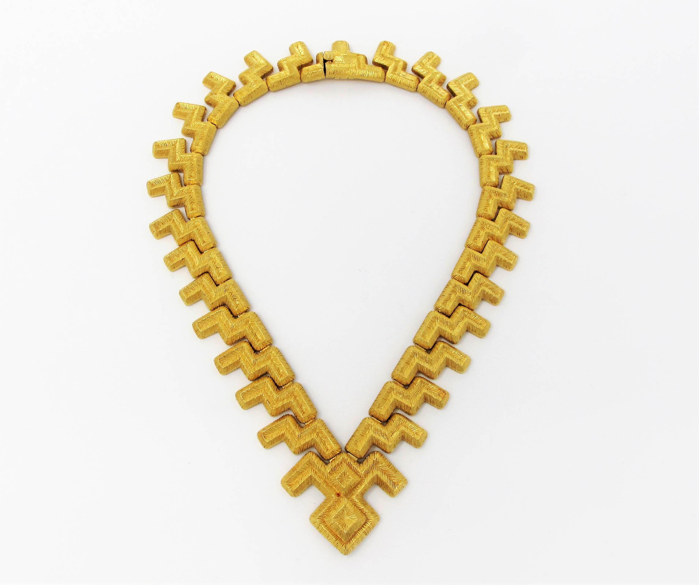 Elevate your style with this sophisticated 18 karat yellow gold zig-zag necklace by Mapamenos Natepas. 

The beautifully made solid gold necklace features textured 18 karat yellow gold zig-zag designs hanging vertically and facing opposite