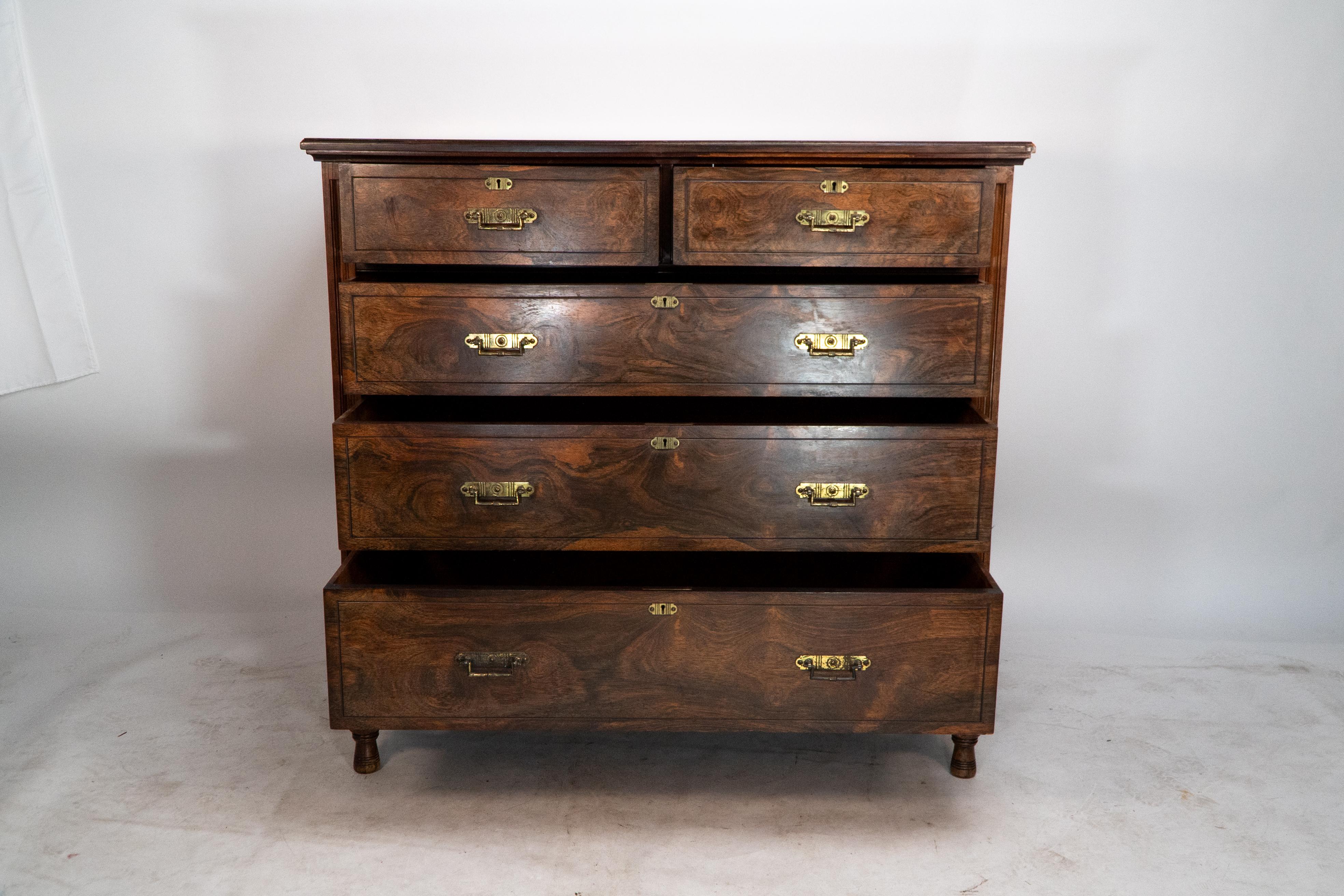 Maple and Co London, in the style of Bruce Talbert. A good quality Aesthetic Movement chest of drawers made from Walnut with a wonderful wild figure to the grain. Molded decoration to the sides, brass handles, and escutcheons with an unusual row of