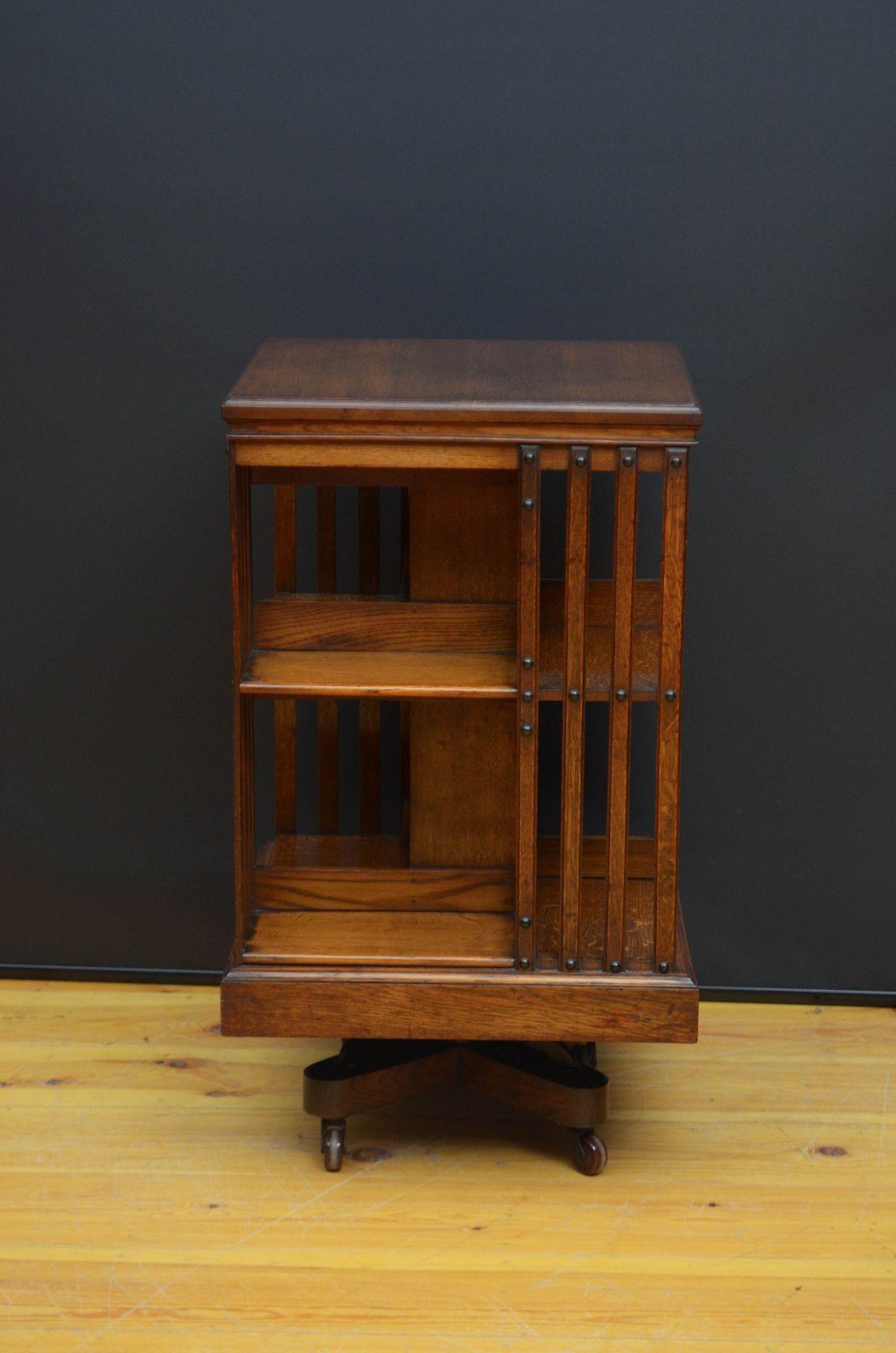 St048 Fine quality Maple and Co solid oak revolving bookcase, having square top with moulded edge above four open sides with reeded slatted uprights, standing on cross stretchers and castors. This antique bookcase bears maker’s label, Maple and Co.