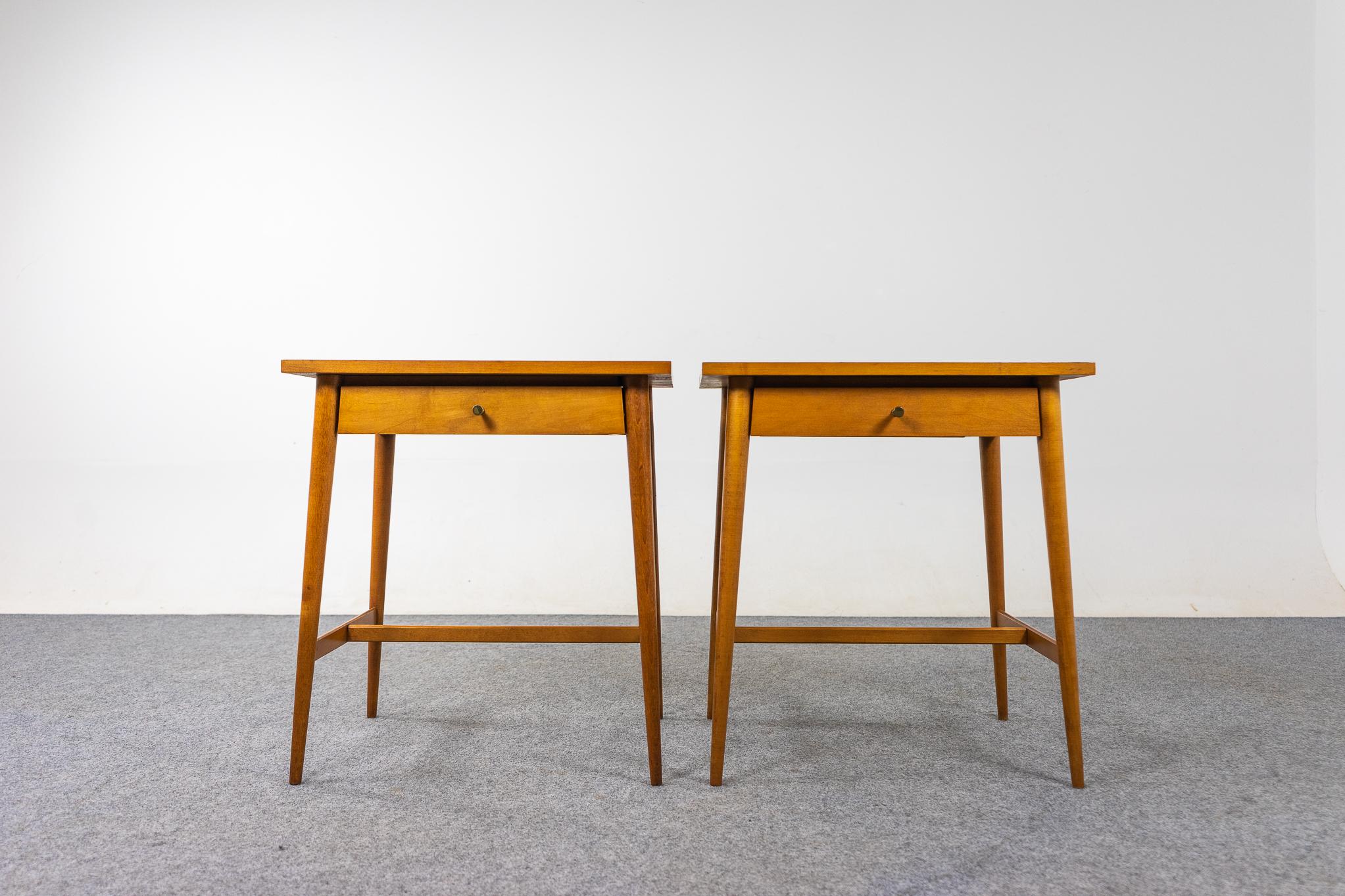 Maple American mid-century bedside tables by Paul McCobb, circa 1950's. Elegant, sleek tables with slender, tapered legs. Slim drawers with metal pulls, keep your evening essentials close at hand. Finished backs make them perfectly suited for use as