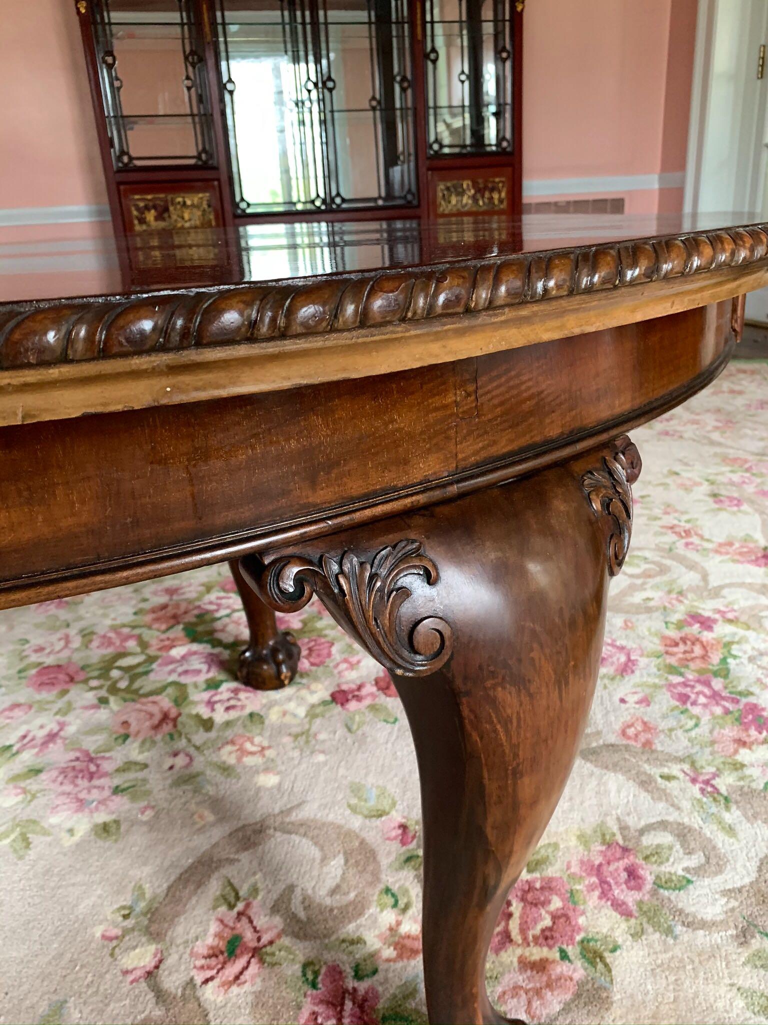 English Chippendale style dining table with four extension leaves made by Maple & Co. The piece has a comfortable seating capacity of 12 people. Each one of the cabriole legs has decorative acanthus leaf carving on the upper leg and a claw & ball