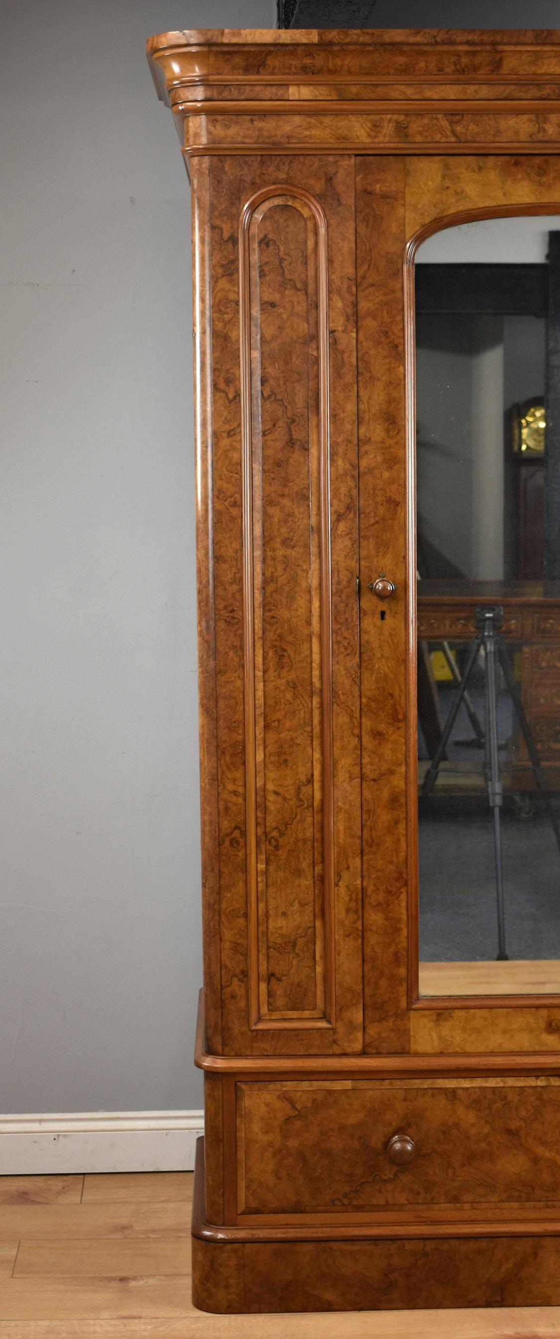 Fine quality Victorian burr walnut wardrobe by Maple & Co in good condition with having a stepped and flared cornice above single mirror door complete with original mercury glass flanked by panels either side above a single drawer with turned