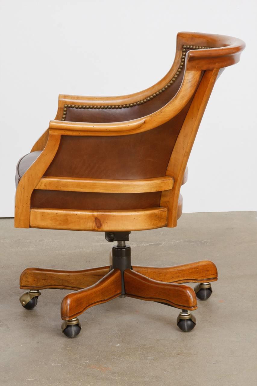 Handsome executive office desk chair by Leathercraft featuring a maple frame construction. Beautifully crafted with leather inserts accented by brass nailhead trim. Fitted with a deep leather cushion the chair is supported by a five leg bottom