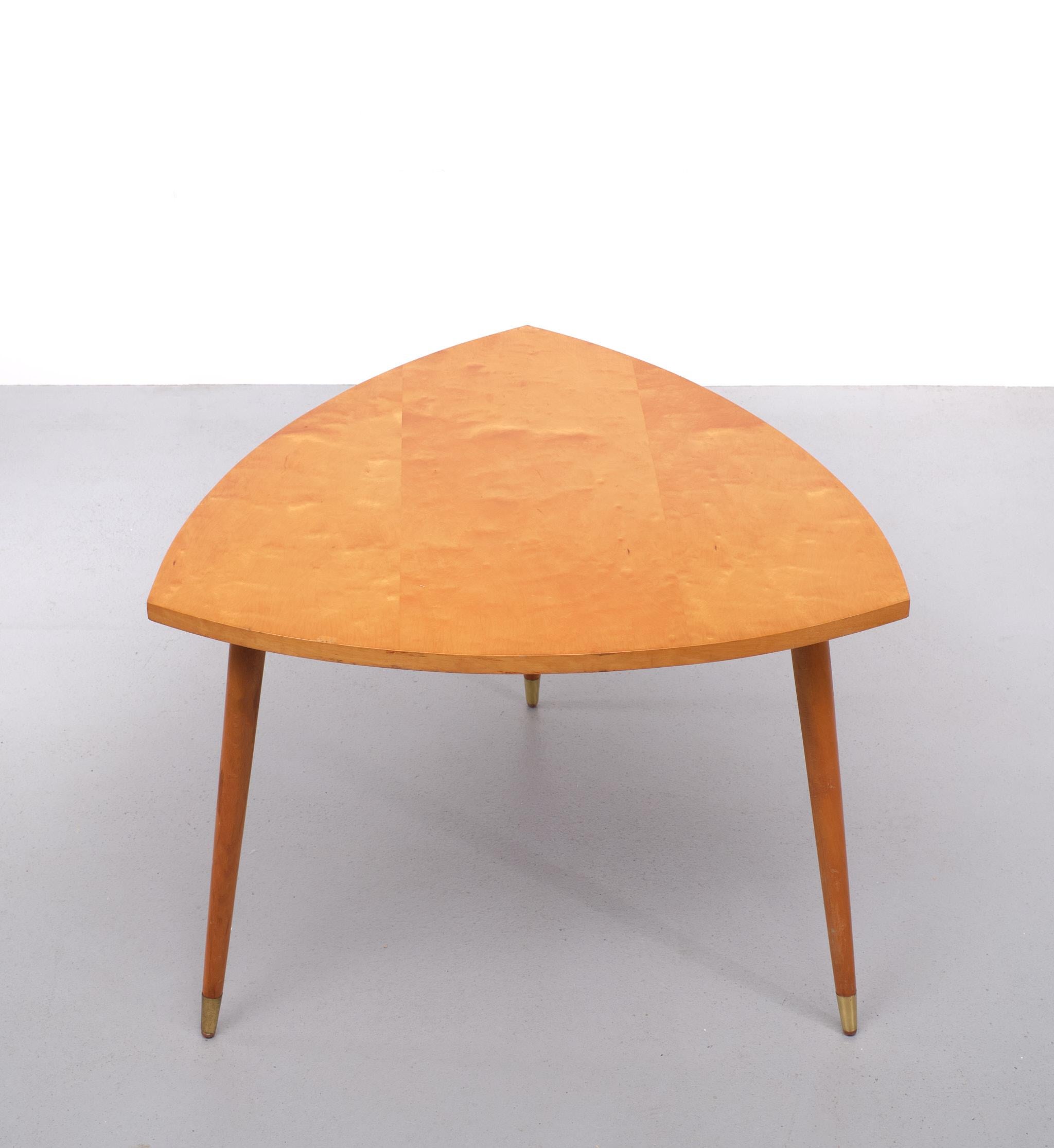 Very nice triangle shaped coffee table, beautiful Maple wood top 
in a warm honey color . Tapered solid Beech feet comes with Brass ends . 
The legs are removable . 1950s  Holland 

Please don't hesitate to reach out for alternative shipping quote