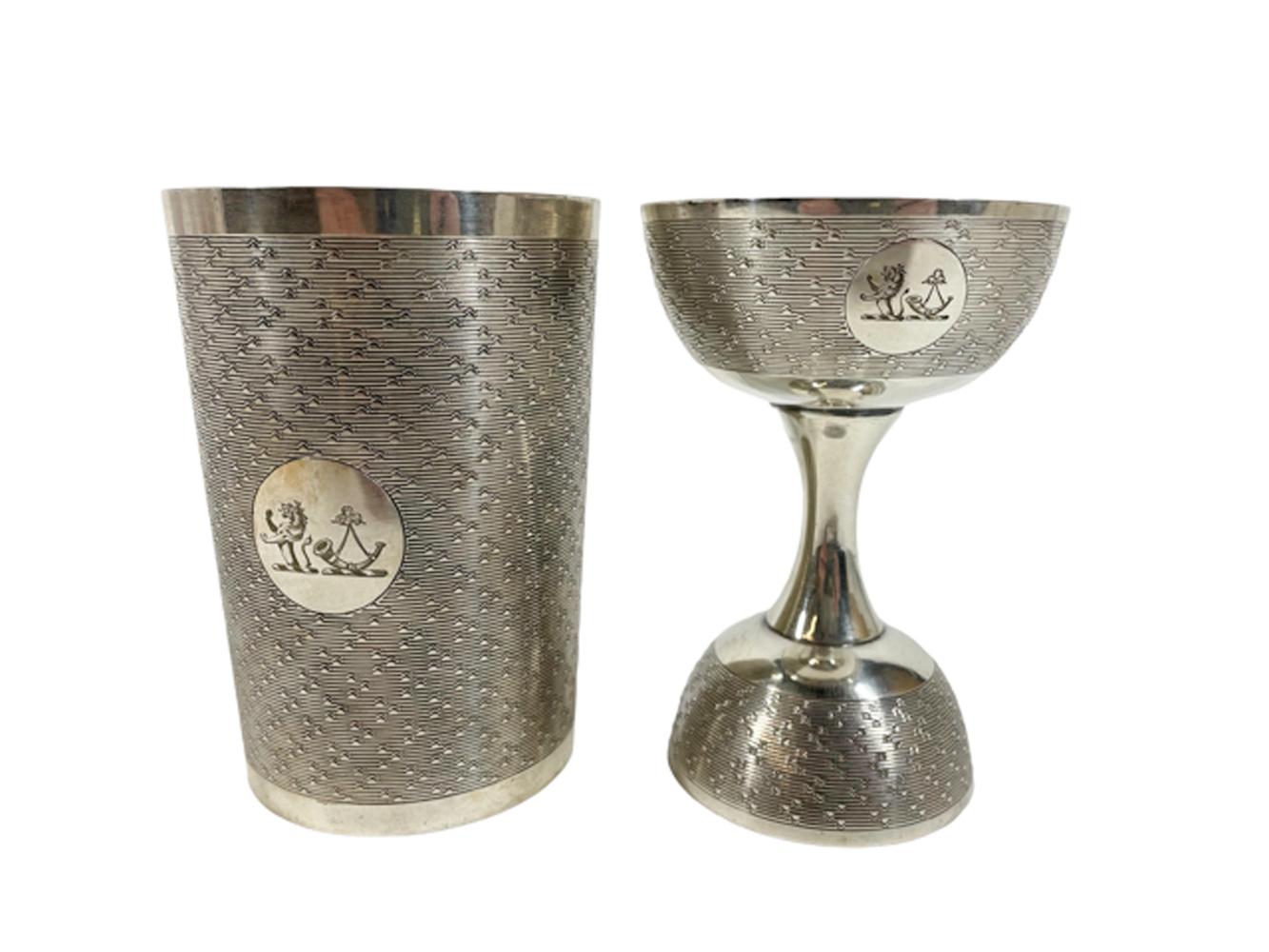 Silver plate double jigger / spirit measure and companion muddling cup. Each with a reserve engraver with a rampant lion and powder horn against an engine turned ground. The measure fits into the muddling cup for storage. Marked under a 