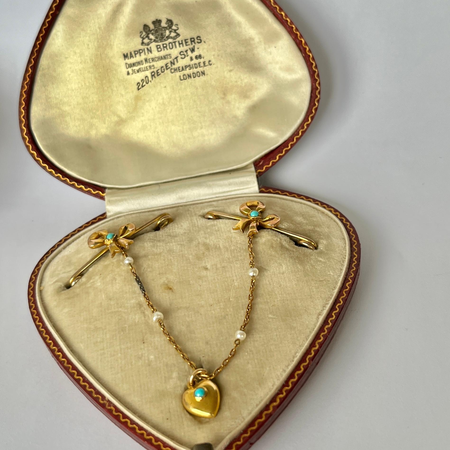 This fancy Mapin Brothers Victorian brooch holds a scattering of small bright turquoise stones and pearls. The two pins have bow detail and the chains hold a sweet heart. Comes in original fitted box. 

Length of Pins: 3.5cm
Heart Dimensions: