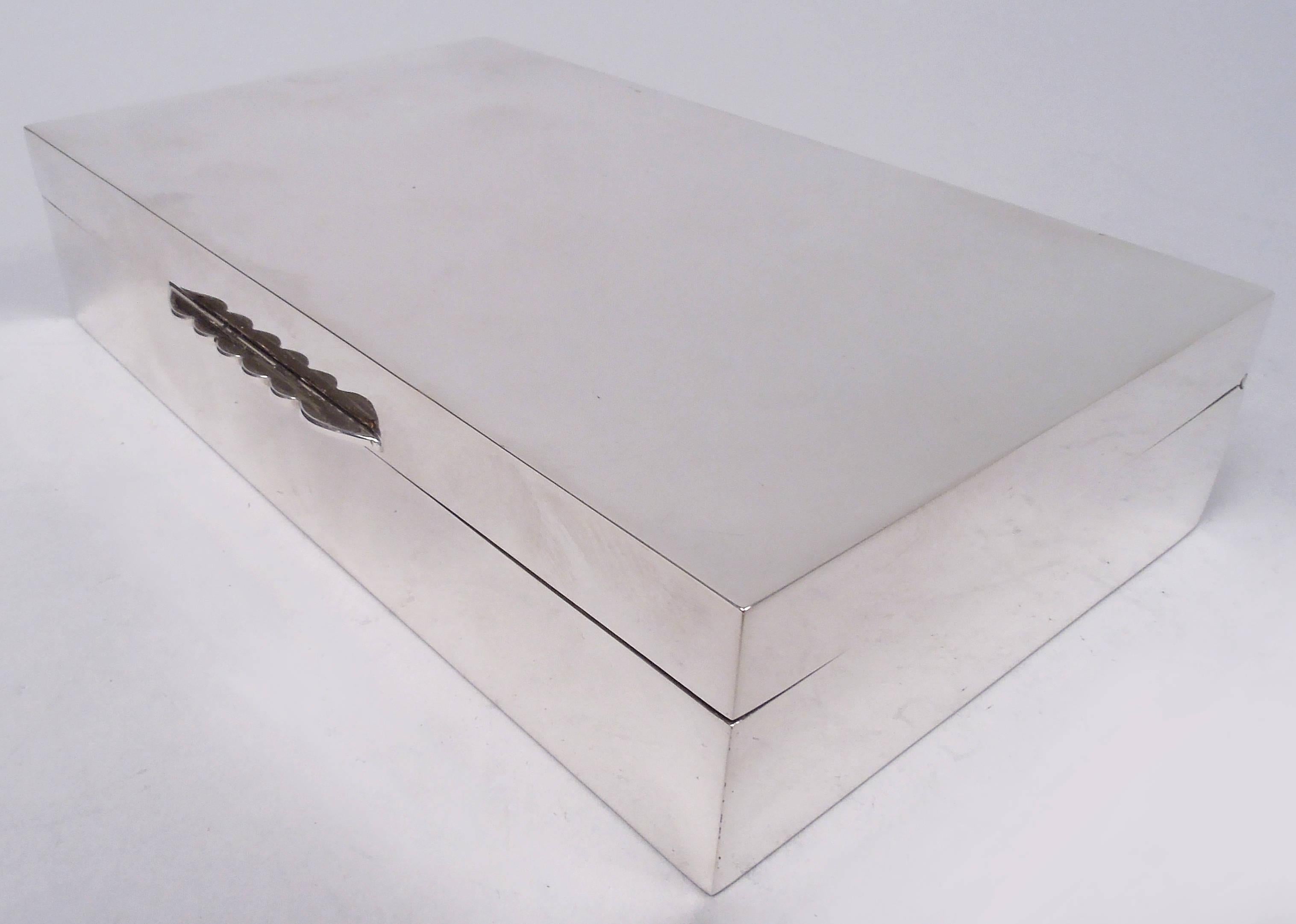 Elizabeth II sterling silver box. Made by Mappin & Webb in Birmingham in 1965. Rectangular with straight sides. Cover hinged with flat top and scalloped tab. Interior cedar-lined and partitioned. Underside leather-lined. Fully marked. Gross weight: