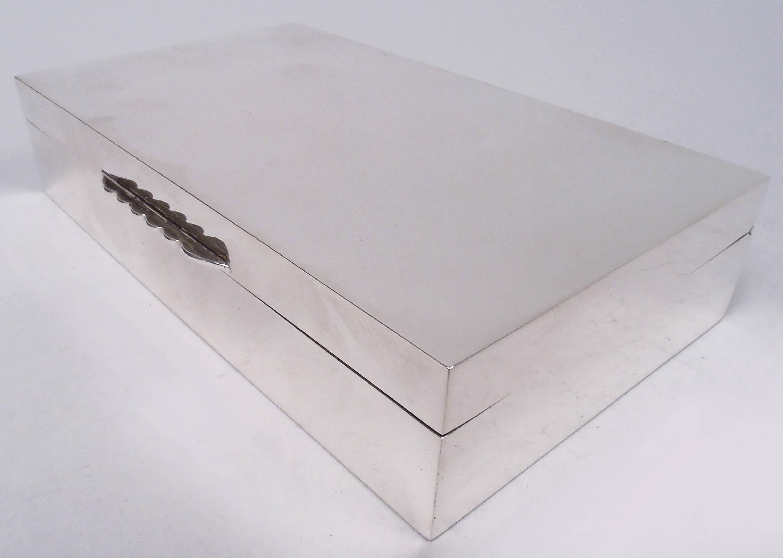 Caja de plata de ley de Isabel II. Fabricado por Mappin & Webb en Birmingham en 1965. Rectangular con lados rectos. Tapa abatible con parte superior plana y lengüeta festoneada. Interior forrado de cedro y tabicado. Parte inferior forrada de cuero.