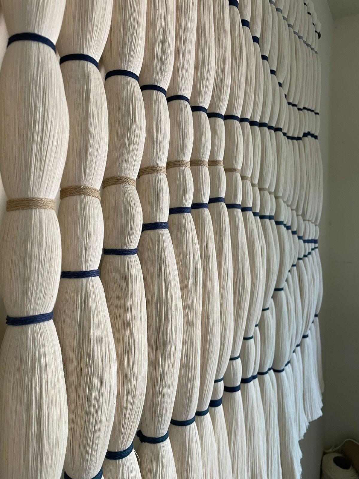 Mar de Algodón ist ein skulpturaler Wandbehang, der den ruhigen Rhythmus und die wellenförmige Bewegung der Meereswellen einfängt. In reiner Handarbeit aus 100 % gekämmter Baumwolle wird jeder Strang in der traditionellen Embarrilado-Technik