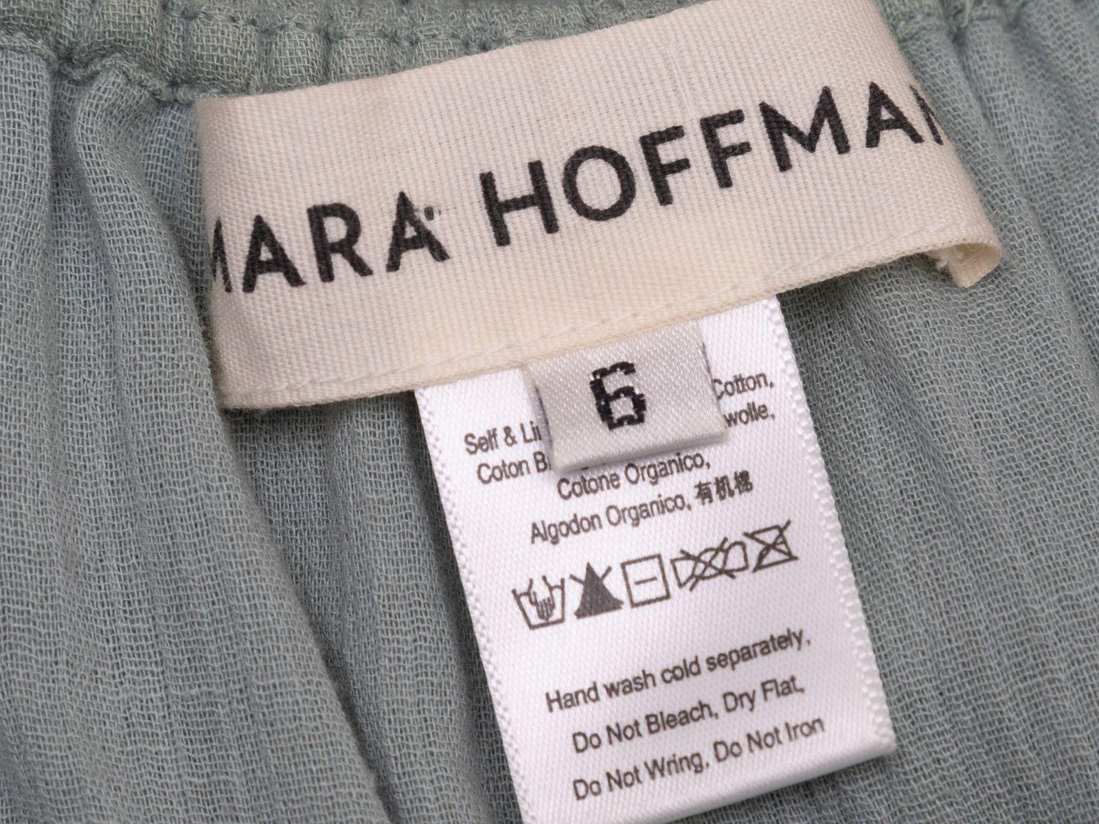 Product Details: Sage green cotton dress by Mara Hoffman. Round neckline. Cap sleeves. Dual hip pockets. Sash tie at back of waist. Button closures at center front. 36