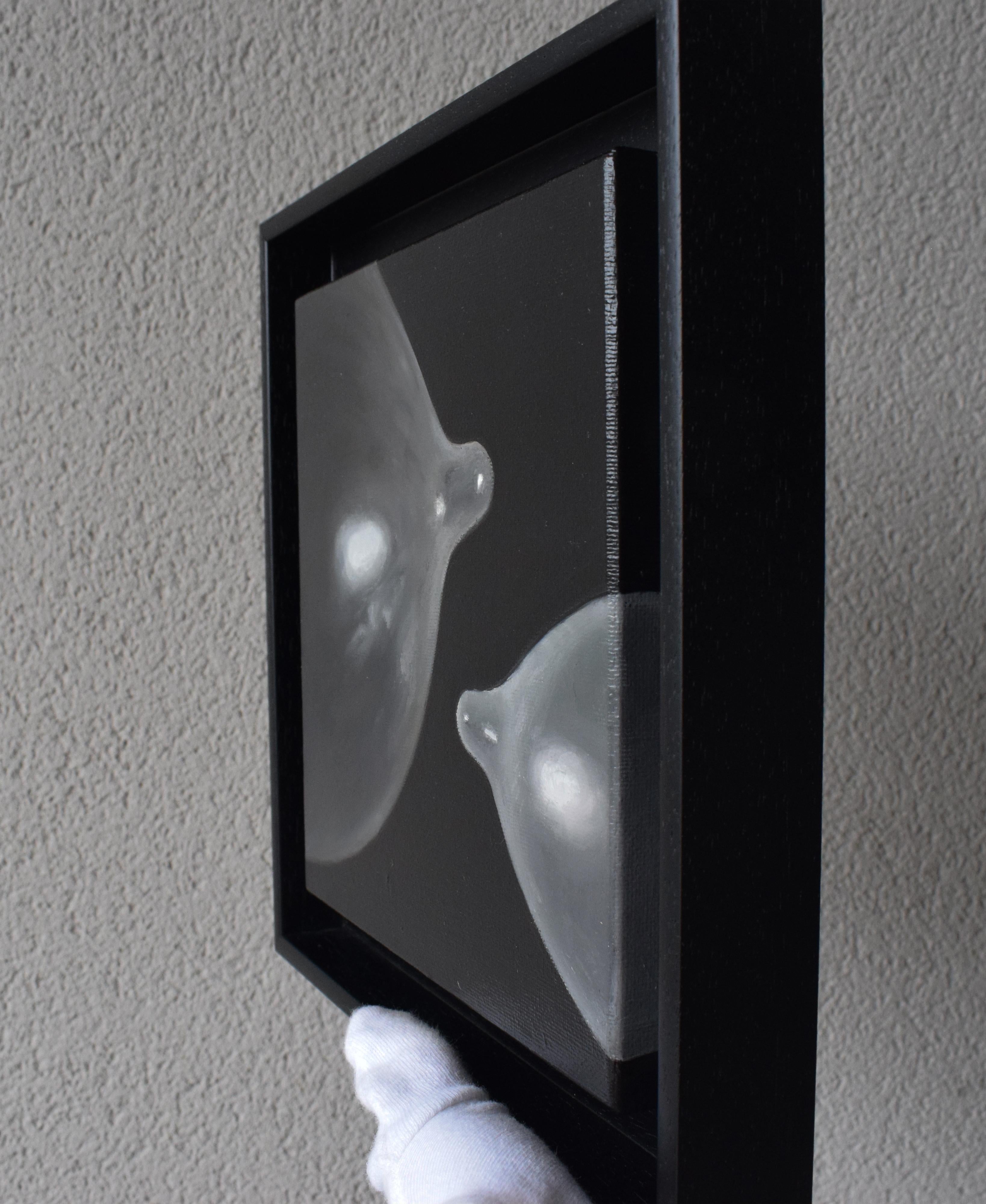 Salt Balloon II is a framed contemporary pop art oil painting that presents two inflated condoms rendered with extraordinary photorealistic precision. Suspended against a deep black background, these condom forms take on a sculptural presence, their