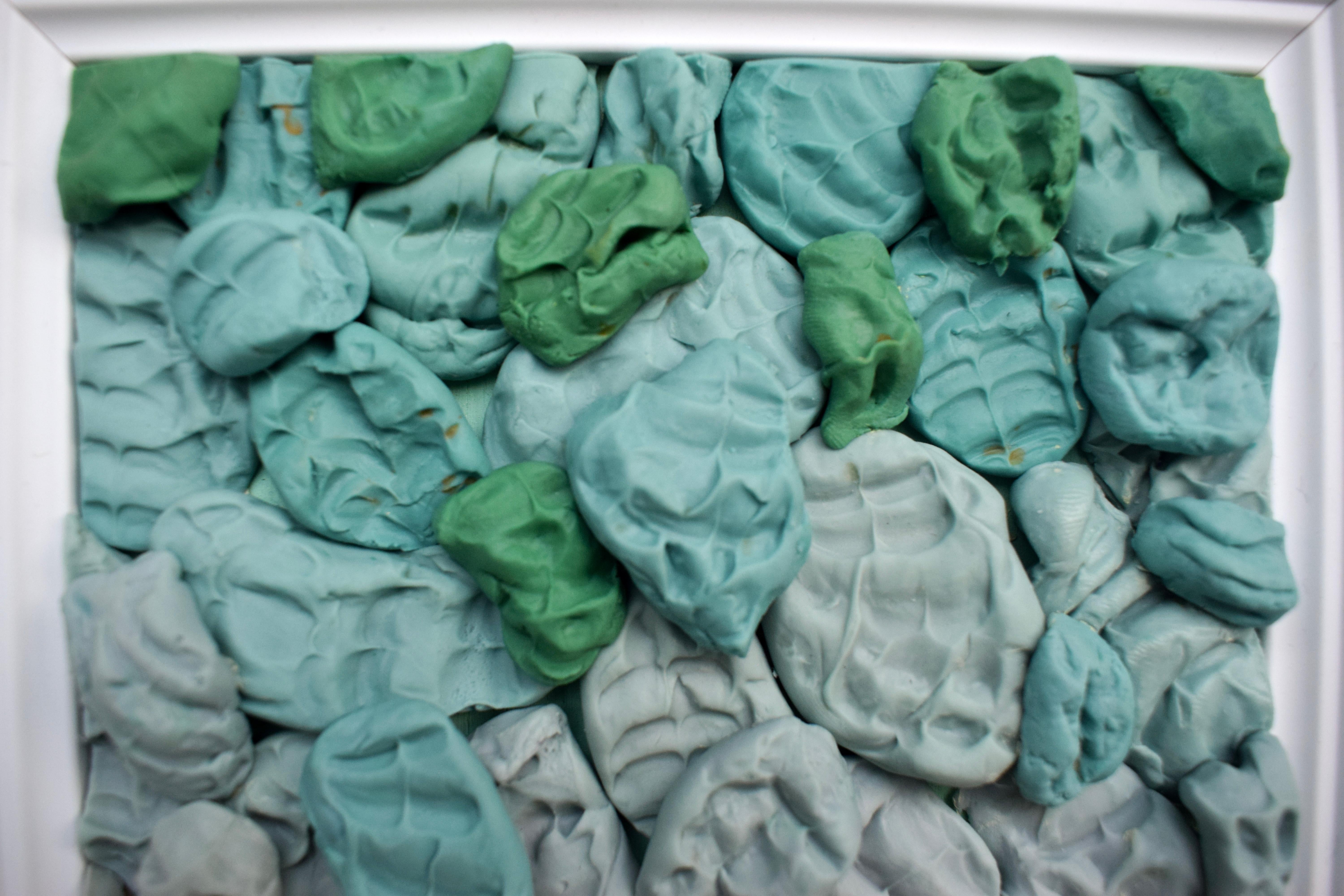 Esta escultura pop de pared de María Magán está formada por docenas de formas de silicona moldeadas a mano y dispuestas en una densa composición degradada dentro de un marco clásico de madera blanca. Hechas de silicona polivinílica -un material