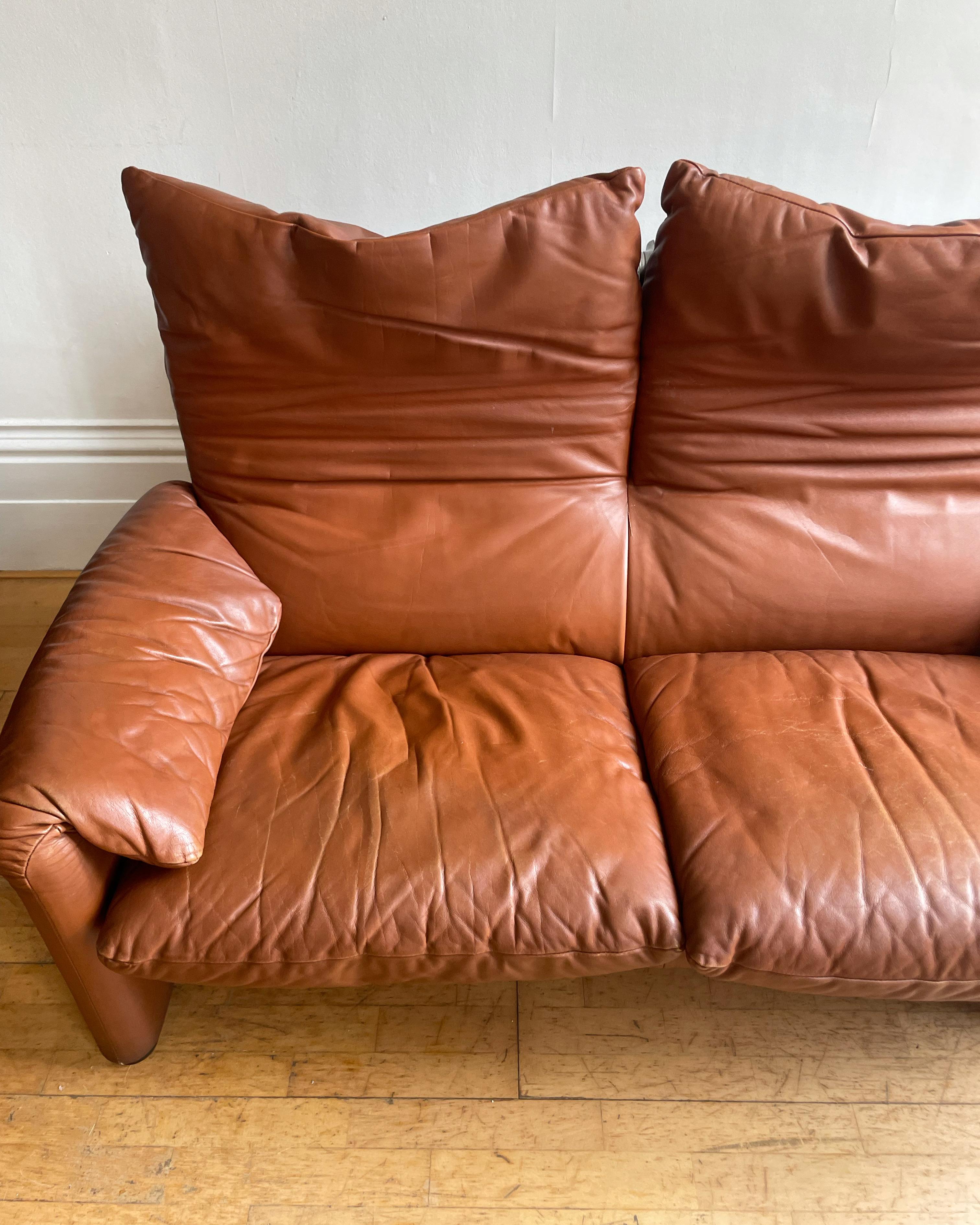 Here is a vintage version of the leather Maralunga two-seater sofa, designed by Vico Magistretti in 1973. It remains with its original tan brown leather, still in good condition, with some scuffs and creasing to the seating as documented, as well as