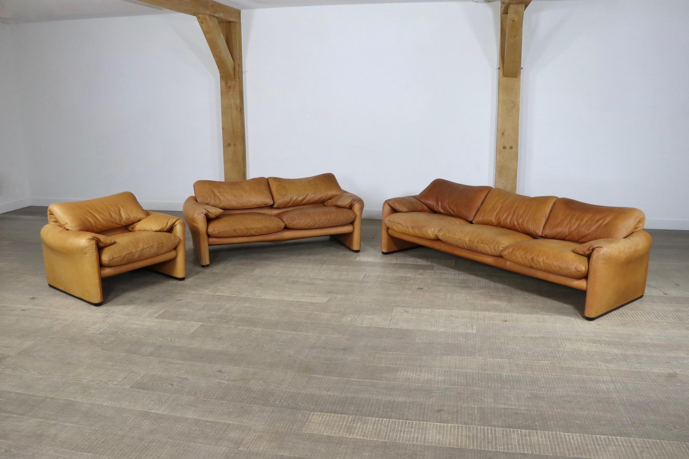 Stunning set of two Maralunga sofas and a lounge chair, by Vico Magistretti for Cassina in the original cognac leather upholstery which has obtained a beautiful patina over the years. 
This design is known for its high comfort and adjustable