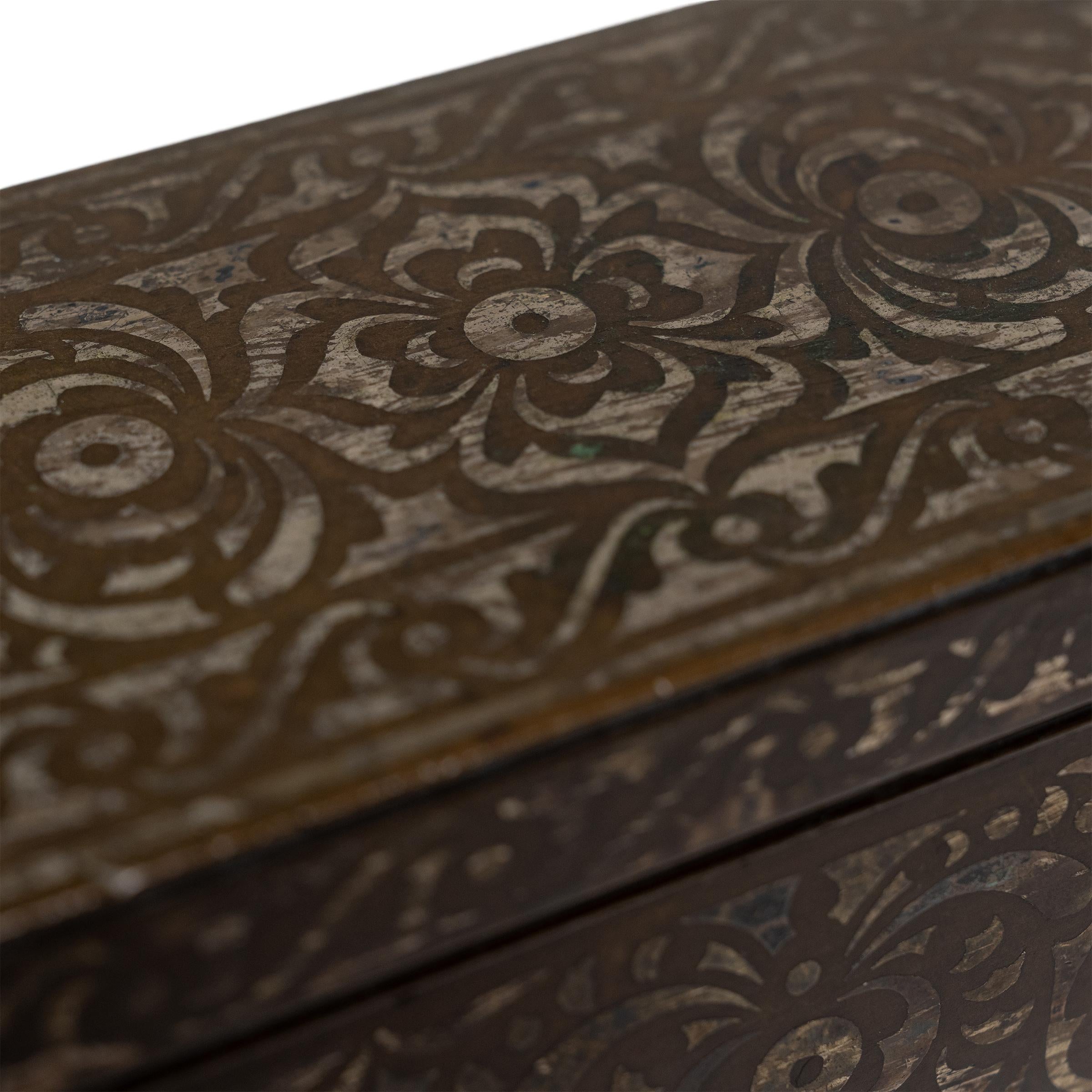 Decorated with silver inlay and cloaked in an antique patina, this curious brass case is an early 20th century betel nut box, attributed to the Maranao people of the island of Mindanao, Philippines. The rectangular box is decorated across the