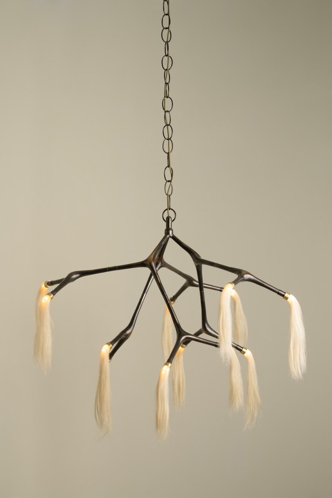 Maratus Horsehair Pendant Lamp by Isabel Moncada
Dimensions: Ø 165 x H 90 cm.
Materials: Bronze, brass and horsehair tassels.
Weight: 14 kg.

A chestnut horse with a white tail is called Palomino, it is dashing and atypical.
This lamp is an allegory
