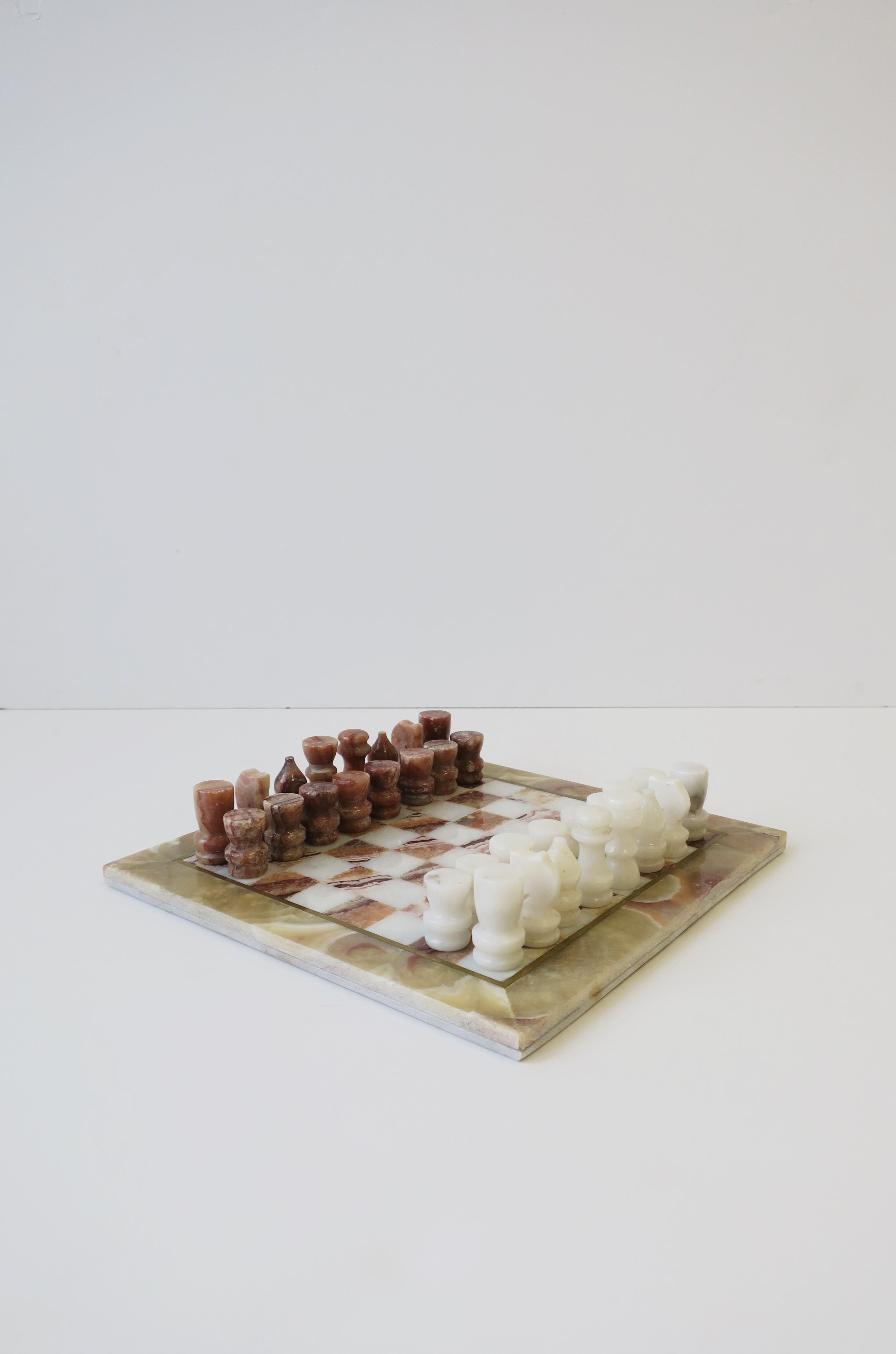 A beautiful and substantial marble and brass chess game set, circa 1970s. Marble game board has a beautiful brass inlay and marble colors that include: white, red burgundy, and light green hues. Game pieces are white marble and red burgundy marble.