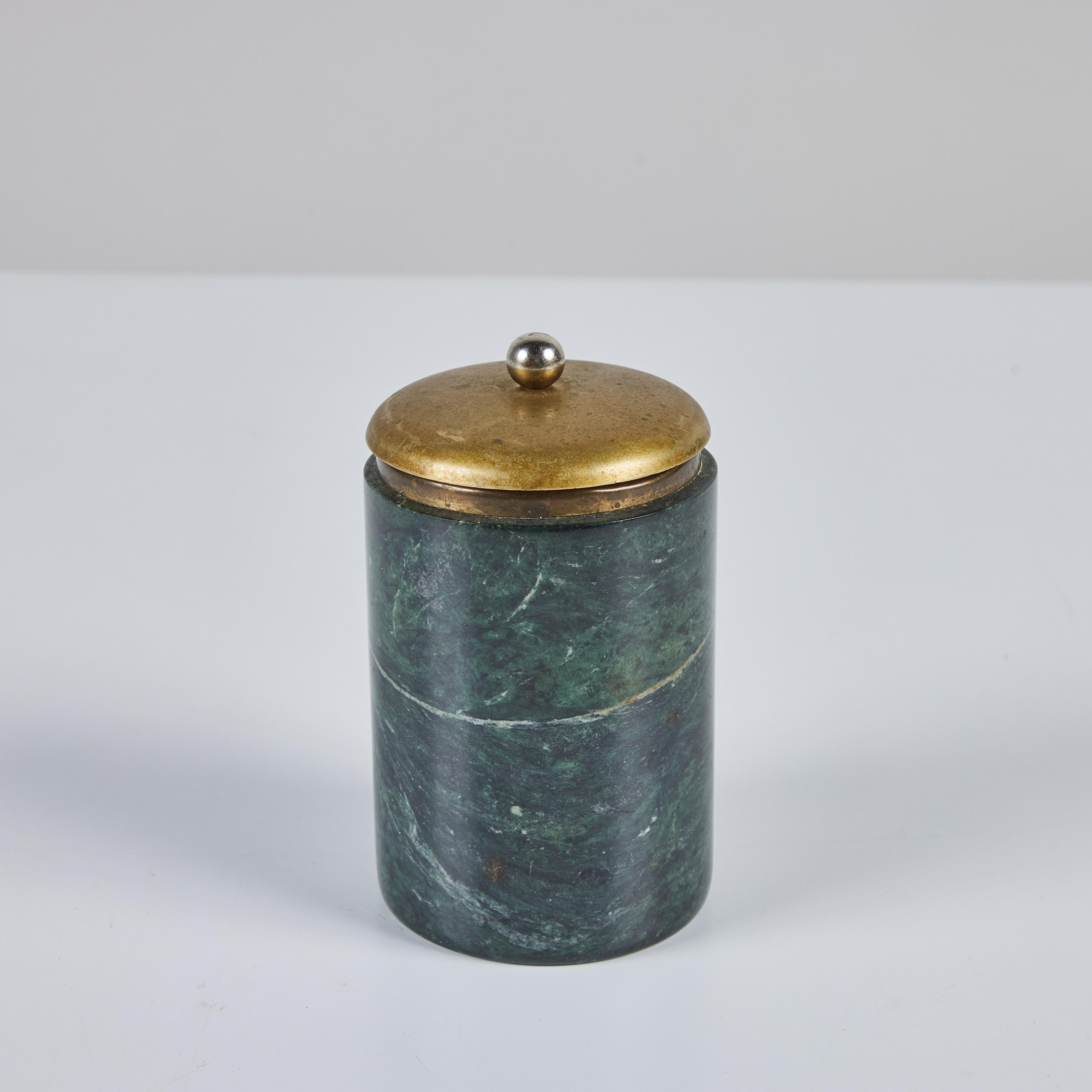 Green marble canister with cream veining features a brass and stainless steel lid. Originally a cigarette holder, it would be perfect for it's intended use or a vessel for q-tips or other trinkets.

Dimensions
3