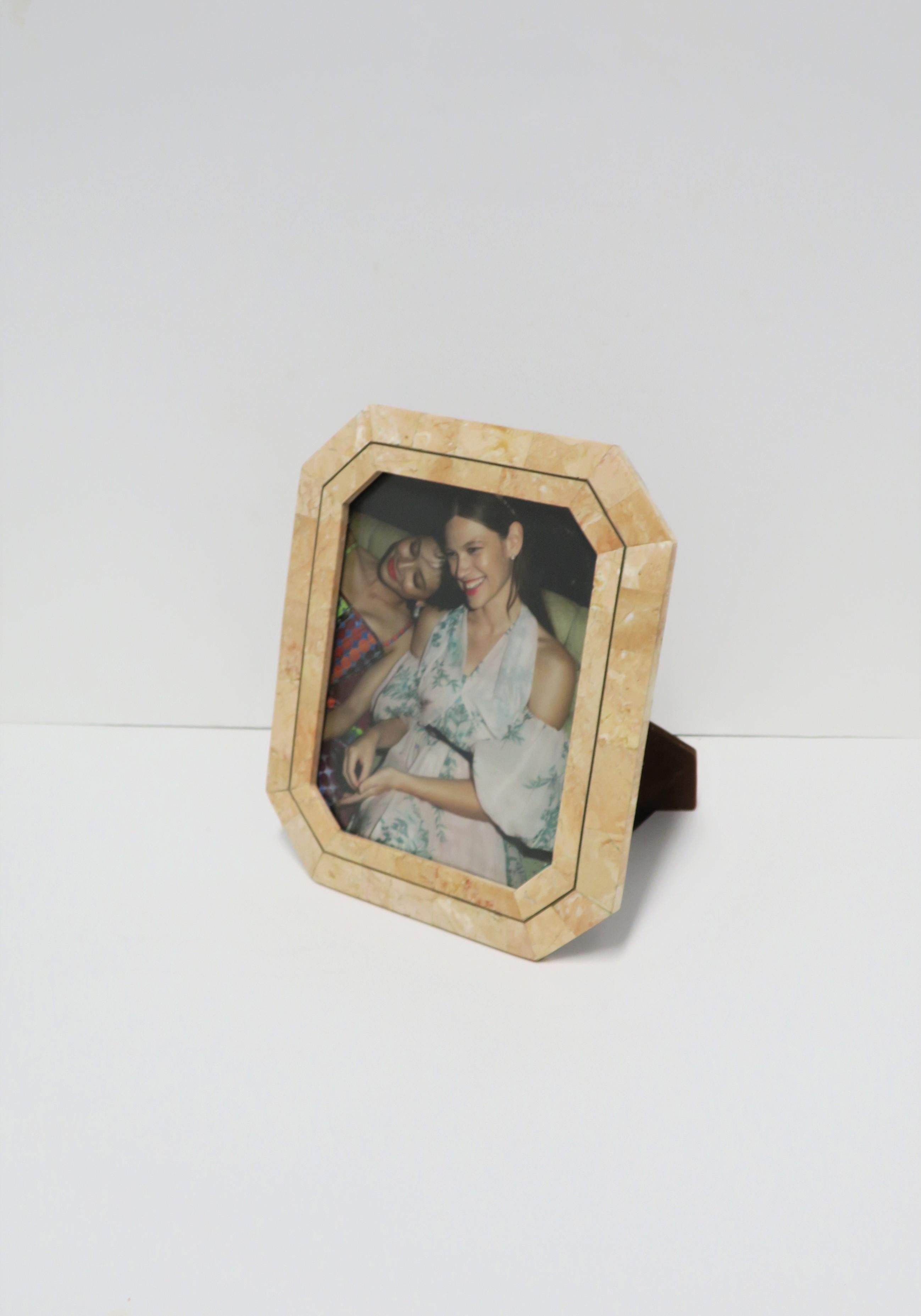 A beautiful '80s marble and brass picture frame by designer Maitland-Smith, circa late-20th century, 1980s. Frame is rectangular/octagonal in shape, and marble in shades of salmon pink and touches of light beige with thin brass detail around. Back
