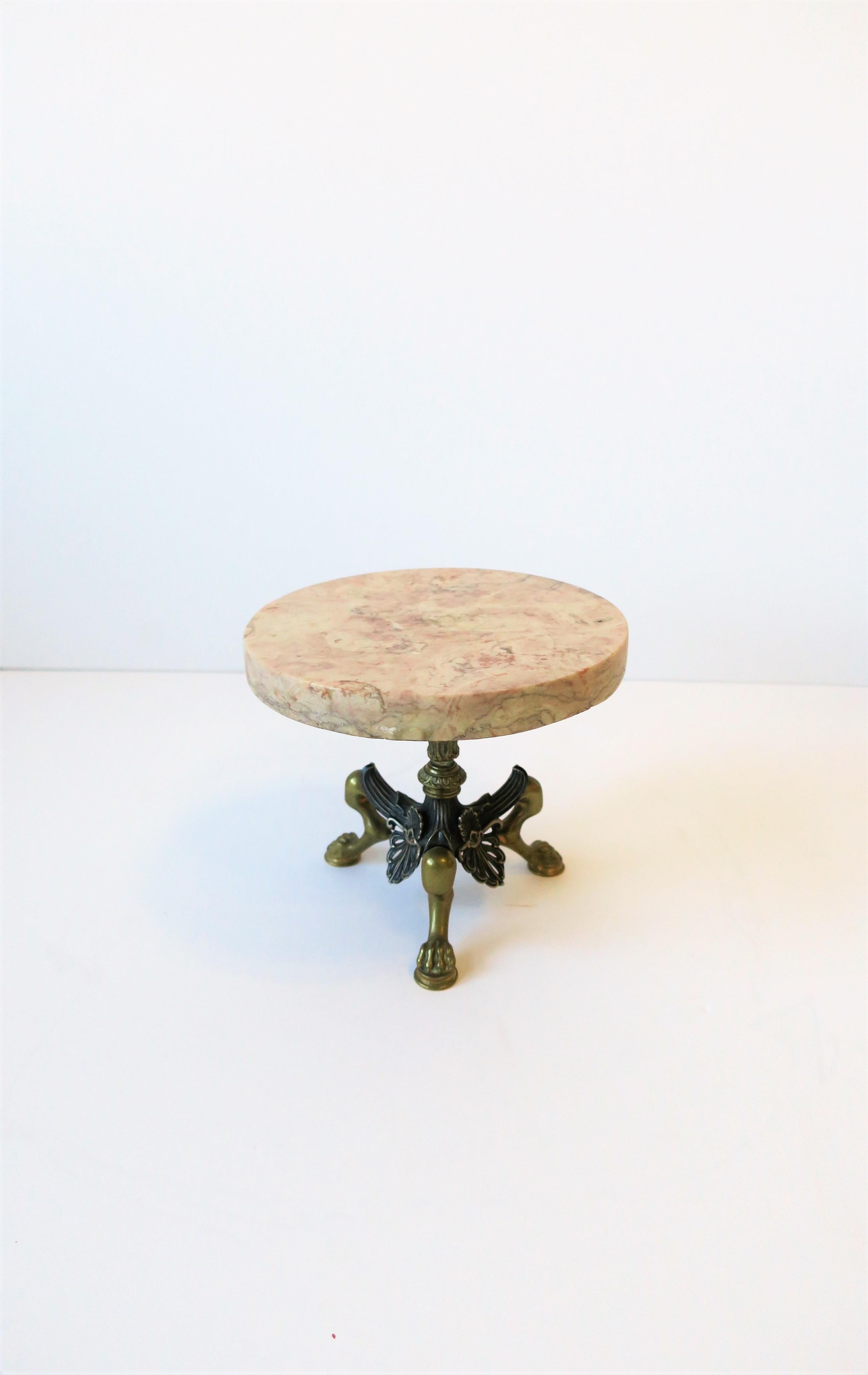 A substantial European round marble and brass pedestal with Lion paw feet base in the Regency style, circa 20th century, Europe. Images #5 and 6 show size comparison. Marble top is a combination of neutral hues and measures almost 1
