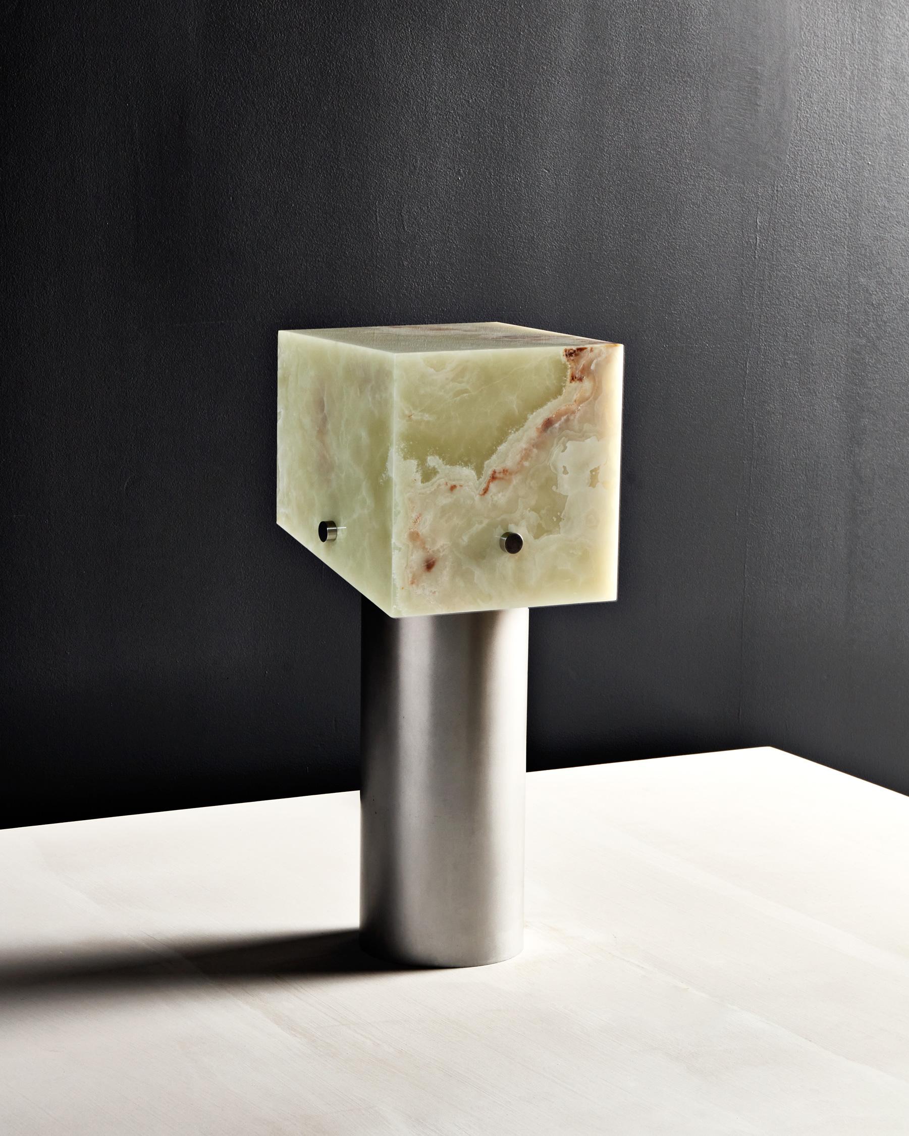The sculptural design of the Mada Lamp plays with balance, translucency, and geometric form to create a harmonious, contemporary piece. The lamp is comprised of a marble or onyx lamp shade which hovers above a cylindrical aluminum or brass base. The