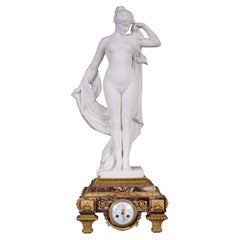 Marble and gilt bronze clock surmounted by a statuary white marble sculpture