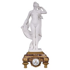 Horloge en marbre et bronze doré surmontée d'une sculpture en marbre blanc statuaire