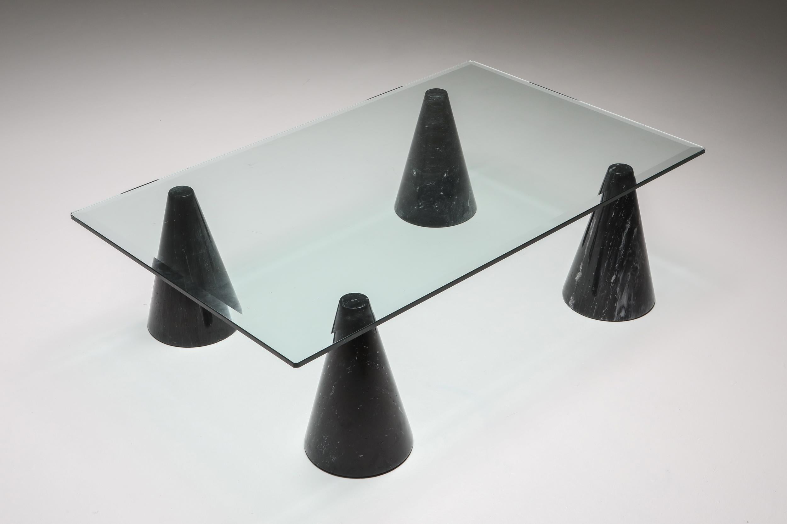 Postmodern Italian coffee table in the style of Massimo Vignelli. 

This features 4 black marbled legs and a thick glass top. Quite a dynamic use of the marble and shapes. The combination of precious marble and glass gives an elegant touch to the