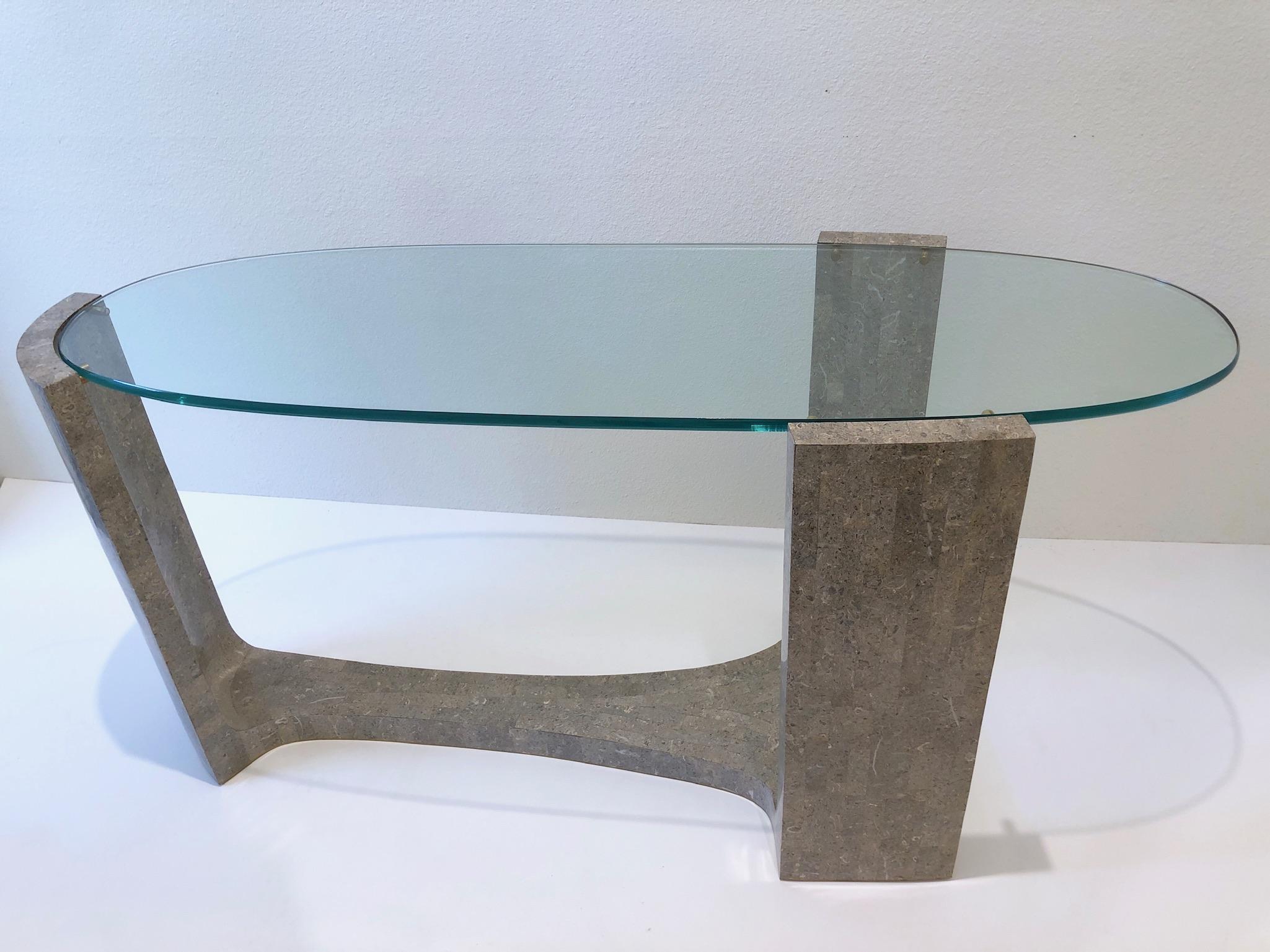 1980’s sculptural console table by Maitland Smith.
Constructed of wood covered with tessellated gray marble, oval glass top and brass details.
Measurements: 28.25” high, 57.5” wide and 21.5” deep.