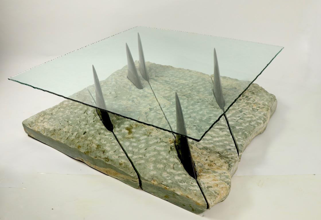 Incredible and probably unique table of marble and glass depicting a school of fish swimming in the ocean, with the fins protruding out of the water to support the glass top. The sea is composed of 4 sections of unpolished textured marble of sea